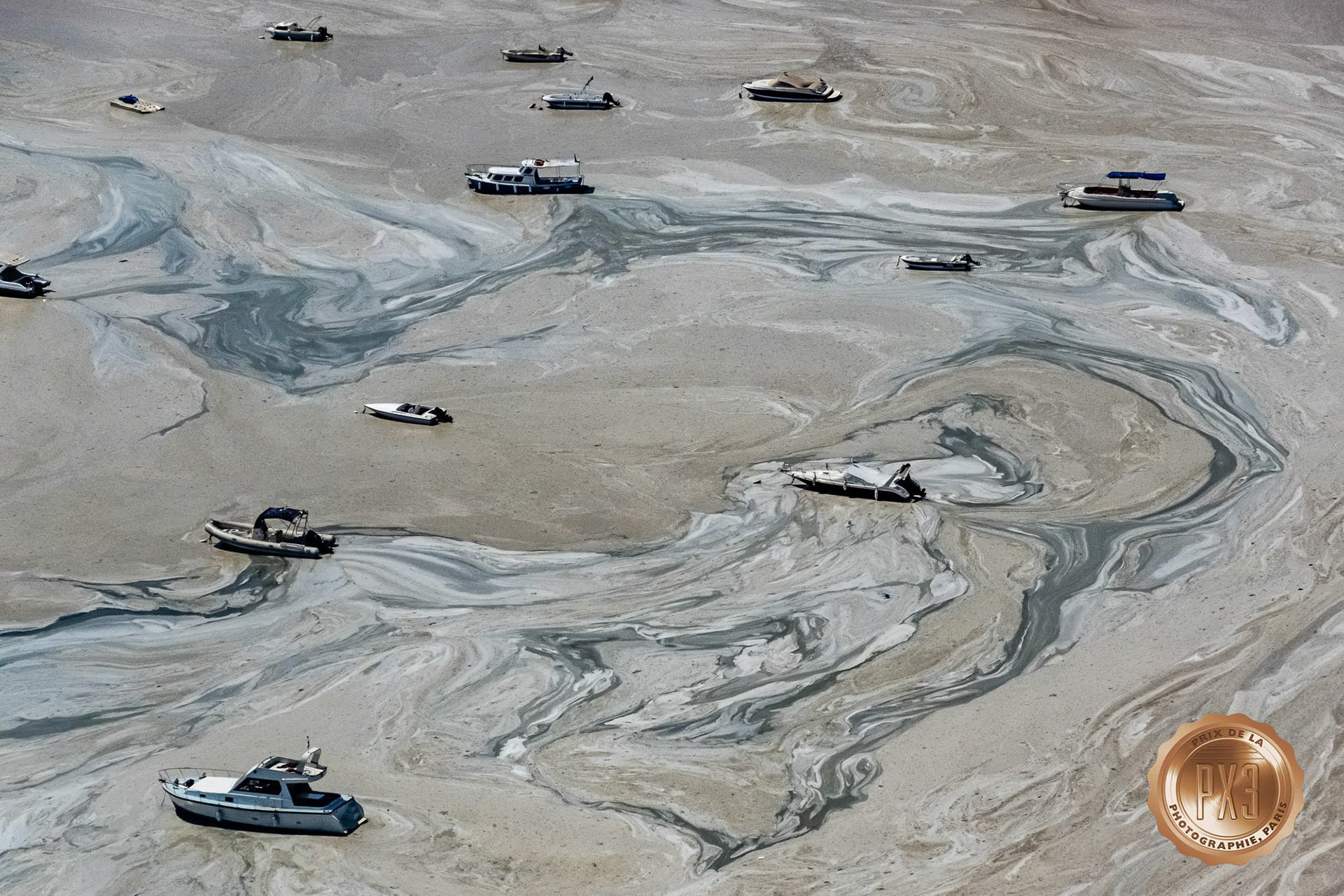 "Mucilage" - Aerial view of boats in mucilage (gluey substance produced by excessive sea microorganisms) at the Marmara Sea coast of Istanbul remind me of marbled artwork. I shot this image while flying in my paramotor for my Flying Detective program on Gain TV. The photograph has won an award in the 2022 PX3 Prix de la Photographie de Paris.