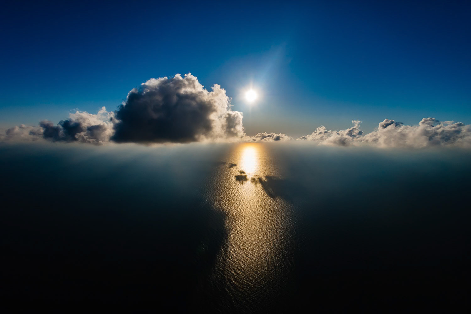 "Cloud Base" - Once in a while I climb in my paramotor really high, to reach the clouds and fly next to or above them. On one occasion, while flying by the Black Sea, I saw a potential image with the clouds and climbed to the cloud base at about 3,300 feet. I shot directly towards the sun to capture the clouds at eye level and the suns's reflection on the very dark Black Sea.
