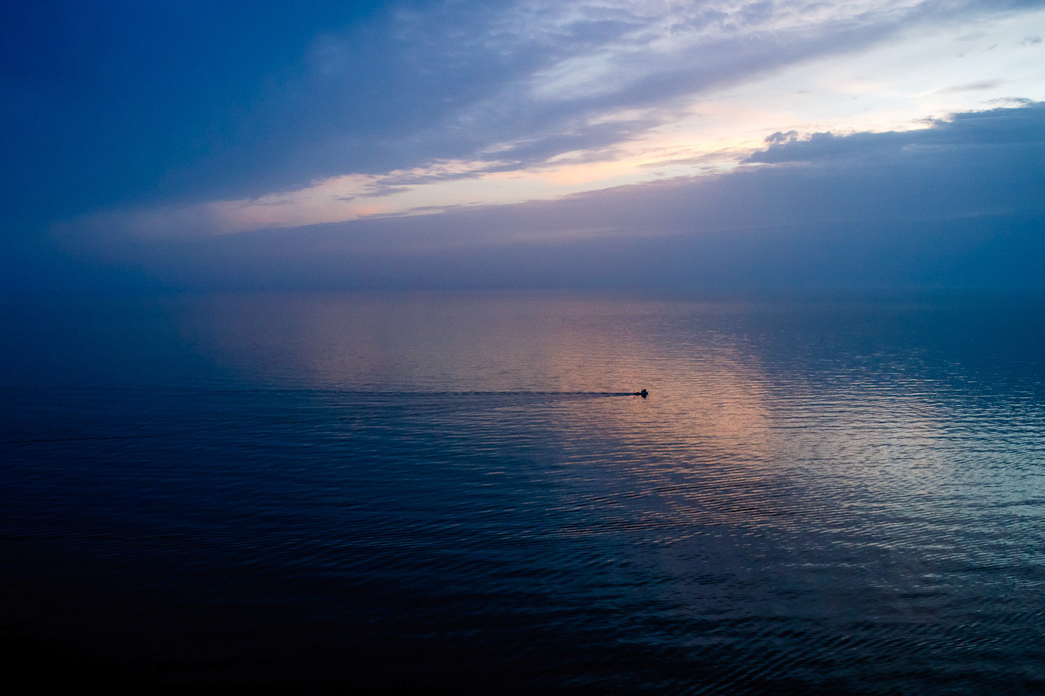 "Marmara" - During a cold November late afternoon flight I saw the solitary little fishing boat on my left side lightly ploughing through the calm Marmara Sea and the pinkish sunlight reflection coming through a slit in the clouds.