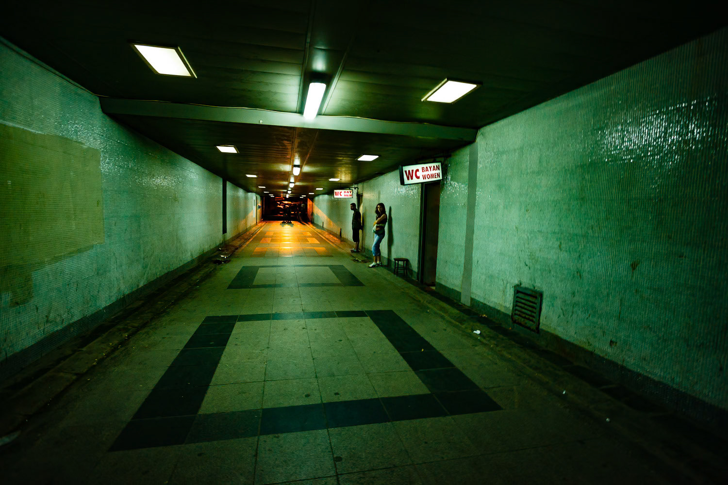 "Underpass" - As I was leaving the passage under the Galata Bridge in Istanbul, I turned around and took this wide angle shot. Green and orange contrasting colors created by artificial lights, strong perspective, a lonely man and a woman waiting in front of public toilets give this photograph an eerie quality.