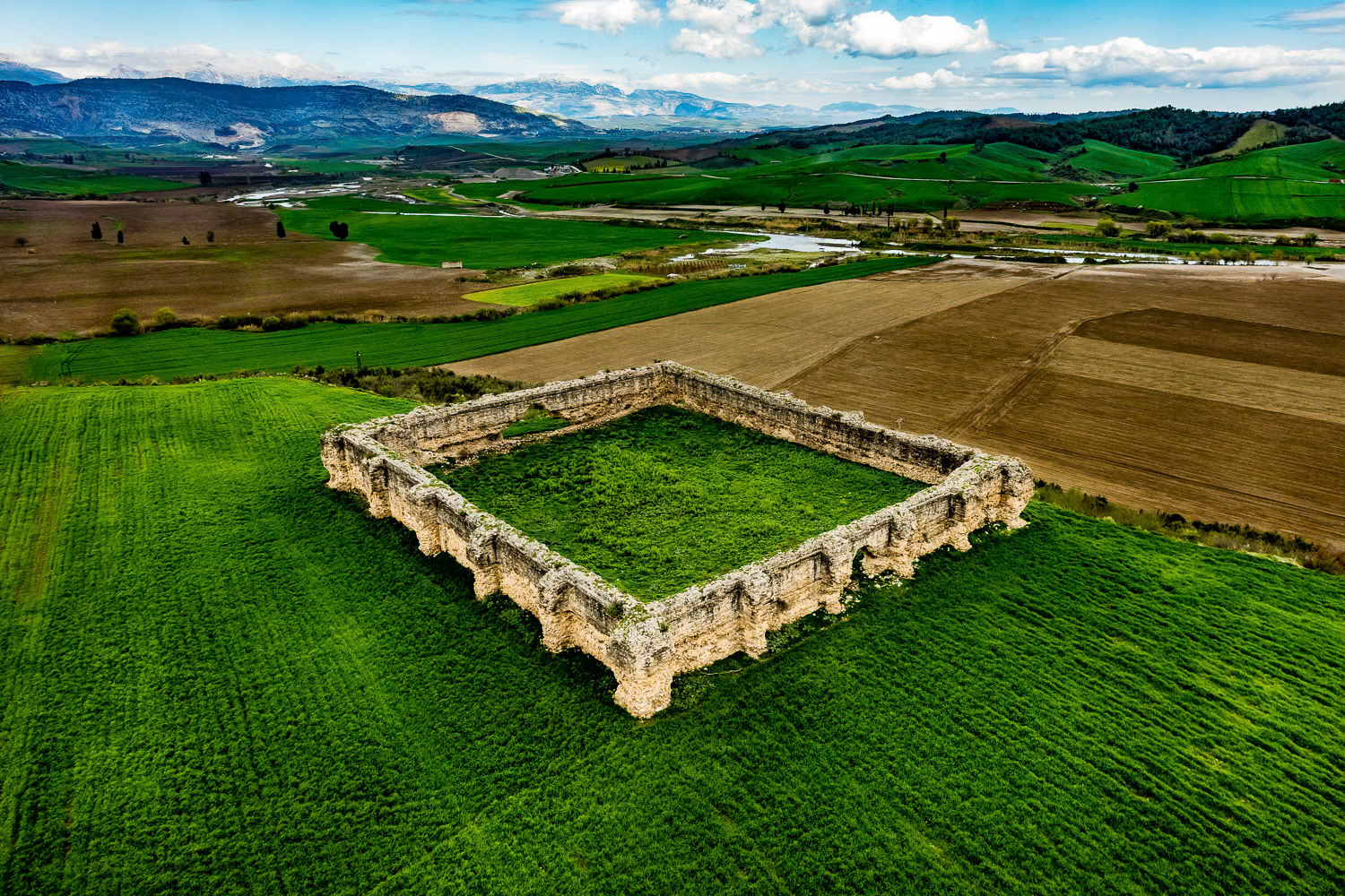 "Kesiri Inn" - During the Crusades, many accommodations and castles were built in this location, which served as the most important gateway from Anatolia to the east. When I came within shooting range, I saw that the dimensions of the inn, the design and the contrast it made with the colors of the cultivated areas were very impressive. It started to rain and I made a pass at the angle that I wanted, shot my frames and decided to land at the first suitable spot. There was only a narrow dirt road between the cultivated fields where I could land safely without getting my wing any wetter. I looked for a sign to determine the wind direction but I could not find any. At that moment, I saw a farmer in yellow boots walking on the road. I flew over, idled the engine and called out, "Where is the wind coming from?" The farmer turned into the wind, moved his two arms up and down, and showed me the direction of the wind in a way that only those in the know can do. I made a short circle and landed safely. The wit of the people of this land surprised me once again.