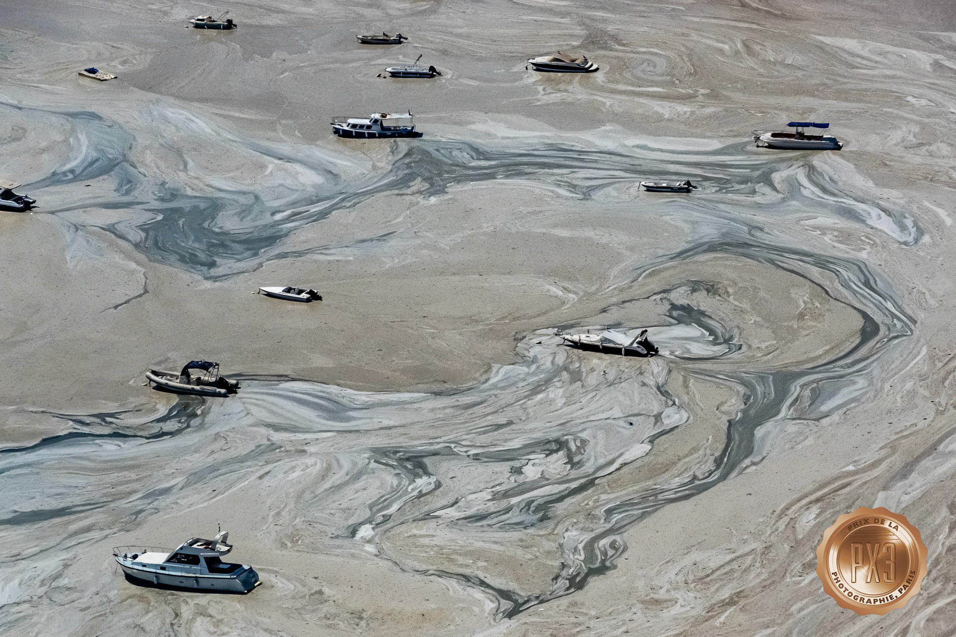 "Mucilage" - Aerial view of boats in mucilage (gluey substance produced by excessive sea microorganisms) at the Marmara Sea coast of Istanbul remind me of marbled artwork. I shot this image while flying in my paramotor for my Flying Detective program on Gain TV. The photograph has won an award in the 2022 PX3 Prix de la Photographie de Paris.