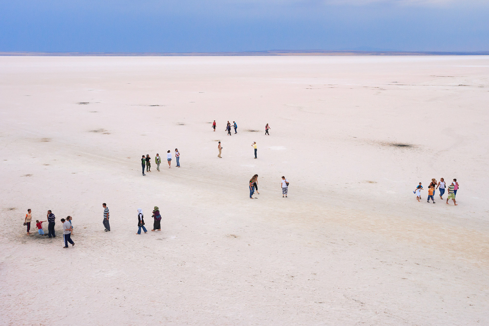 "People on Salt Lake" - People enjoy a leisurely stroll on the endless white salt flats of the Salt Lake.