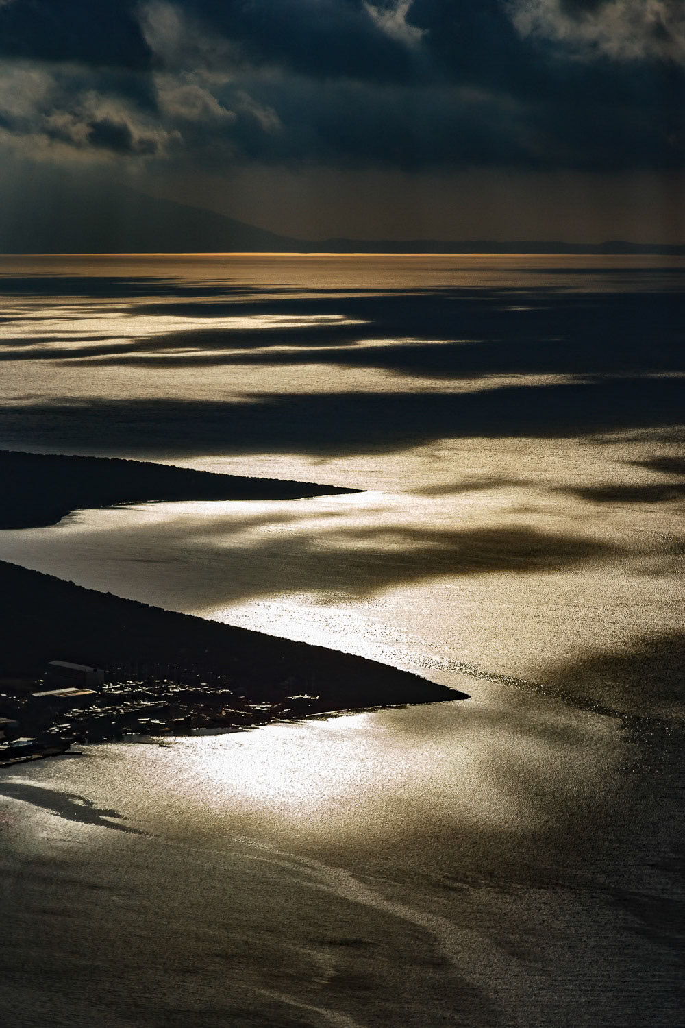 "Light and Shadow" - Clear summer skies are replaced by cloudy days in autumn. During a November flight with my paramotor over Bodrum I loved the play of light and dark on the Mediterranean, two angular pieces of land sticking in from the left side giving context, and the dark stormy weather in the background.
