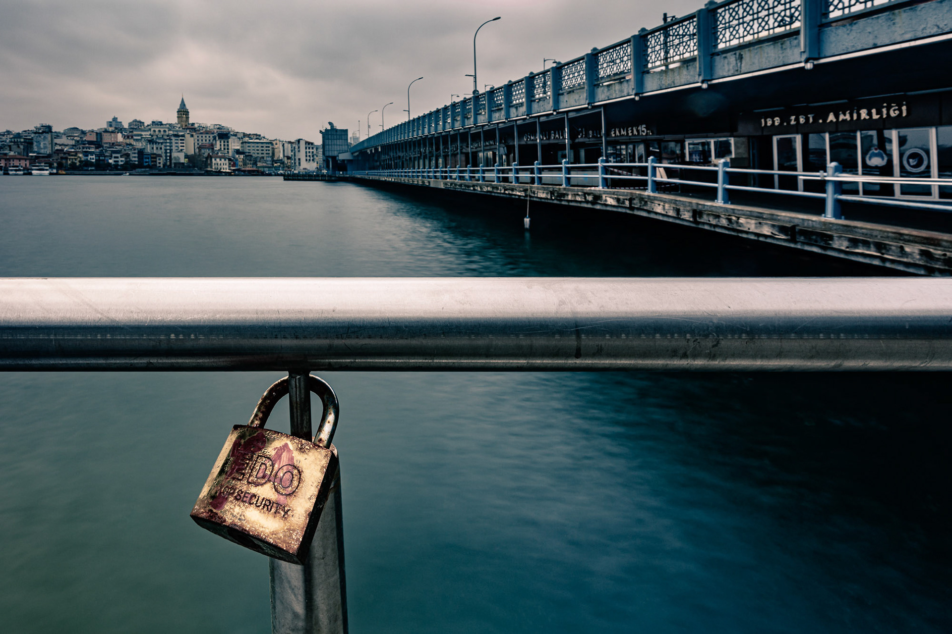 "Locked" - I was photographing on and around the Galata Bridge in Istanbul to document the isolation caused by the Coronavirus pandemic. I saw this rusty lock on the railing serving no purpose, except for possibly a wish, and felt that it was meaningful in the lockdown days. The empty bridge, Golden Horn and the Galata Tower are in the background.