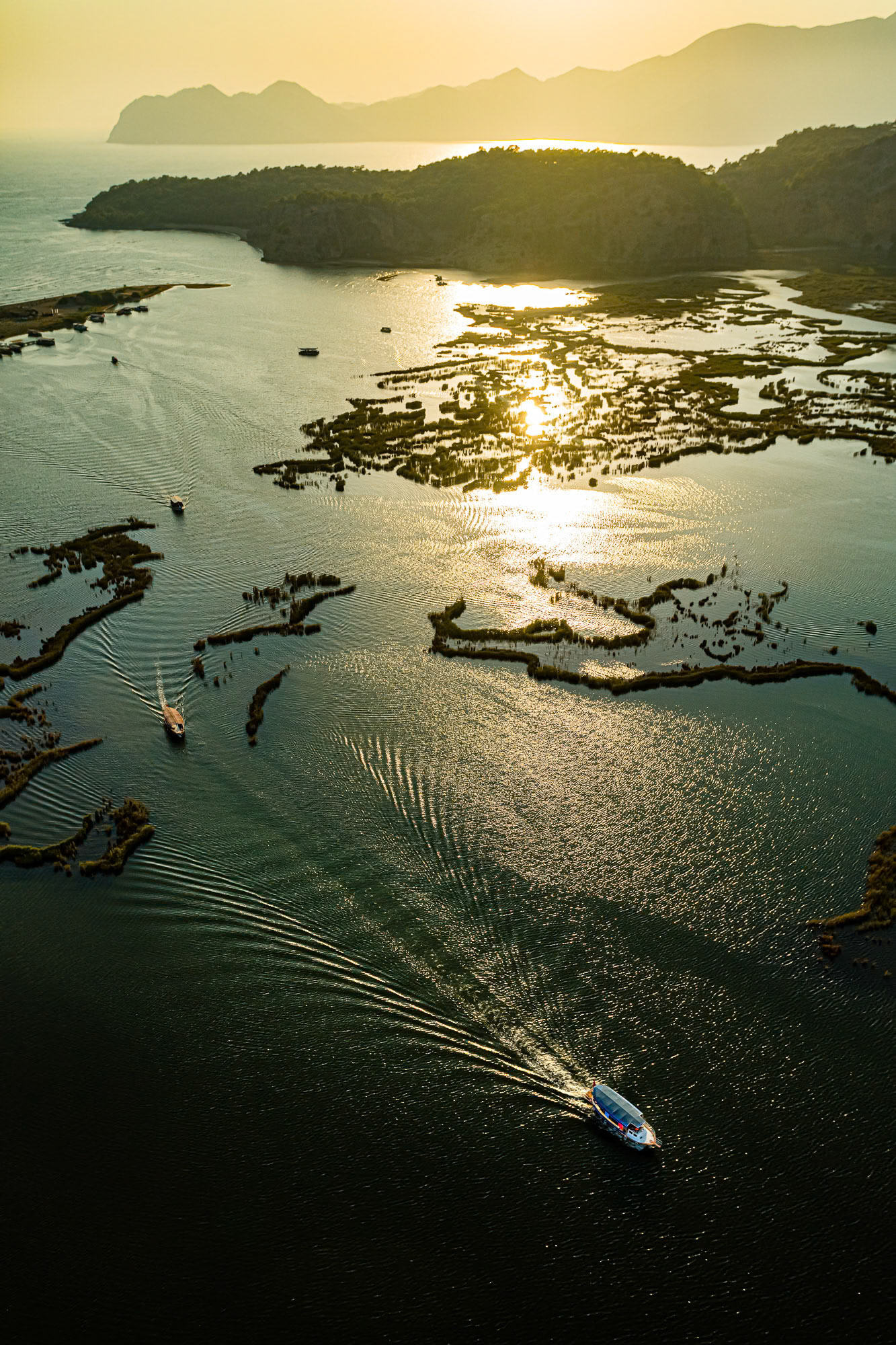 "Reflections of Dalyan" - Sun reflecting off of water as I have seen from the air while flying above Dalyan. The three boats and their wake on the water completed the texture of the image. The greenish color cast gave the photograph a magical quality.