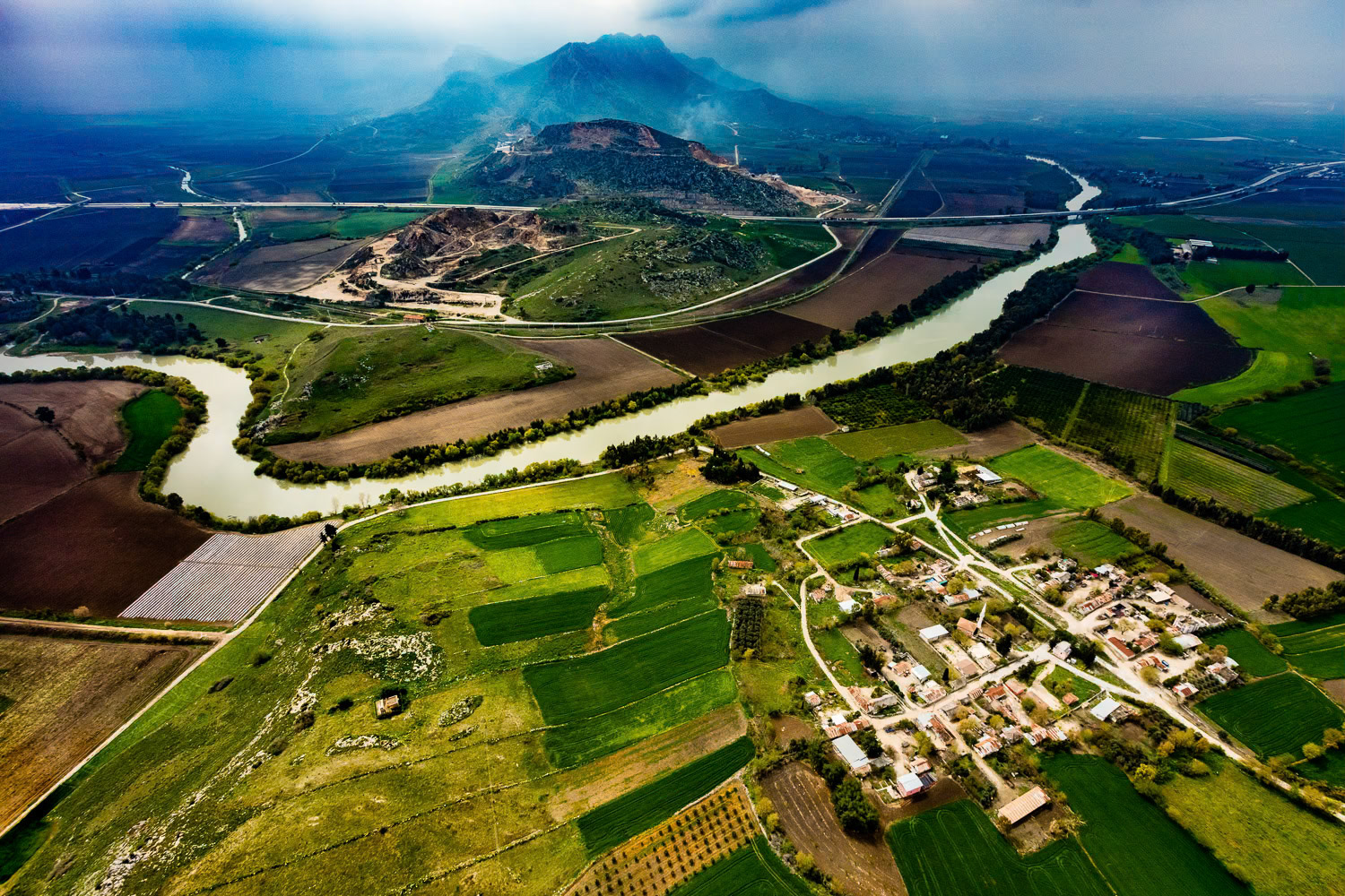 "Küçükburhaniye" - Ceyhan River and Küçükburhaniye Village near Yilankale (Snake Castle). The foggy blue hills in the background, fields of different shades of green and brown, the village of Küçükburhaniye, the meandering Ceyhan river and the modern highway in the form of a thin line reminded me of Far Eastern style landscapes.
