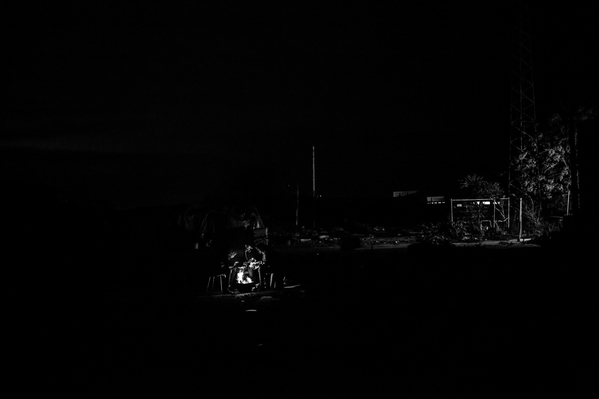 Farm workers in informal camp. The temperature in Sicily, at night, in the period between December and March drops to 4-5 degrees, it is also a period of very heavy rainfall. There is no heating, no water and no electricity in the camp, so firewood is collected from the fields nearby to burn it in metal buckets to warm up for a while.
