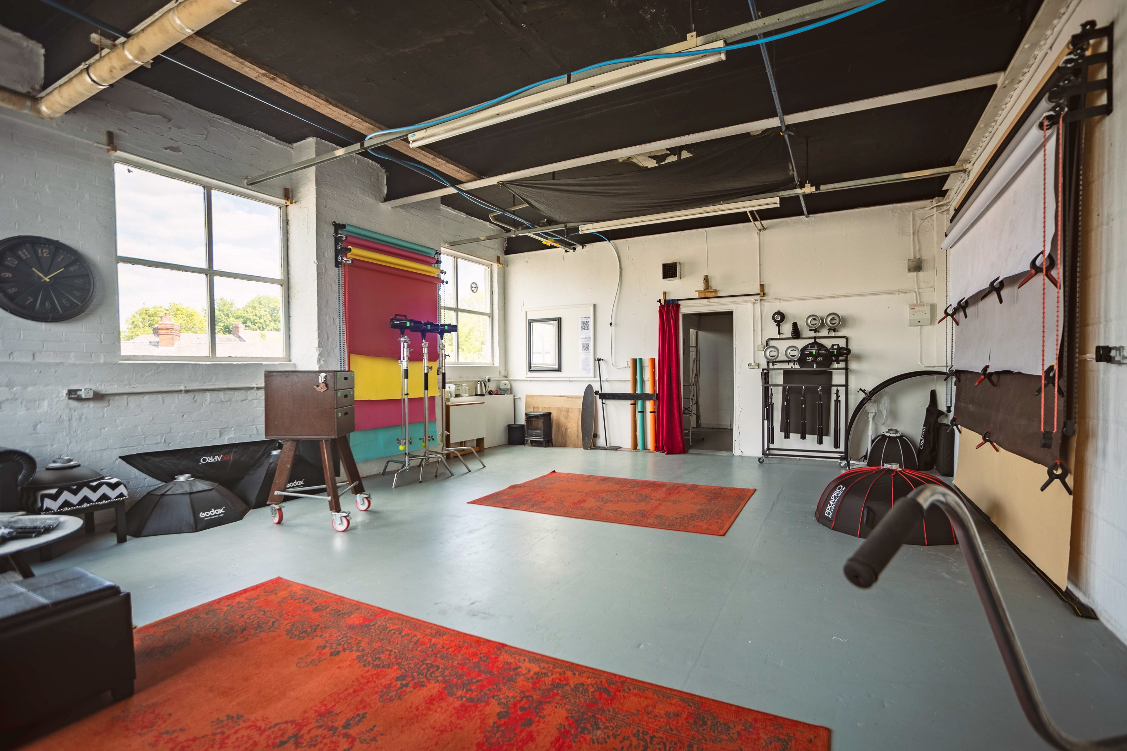 View of a photography studio with large windows, lights, various equipment and backdrops