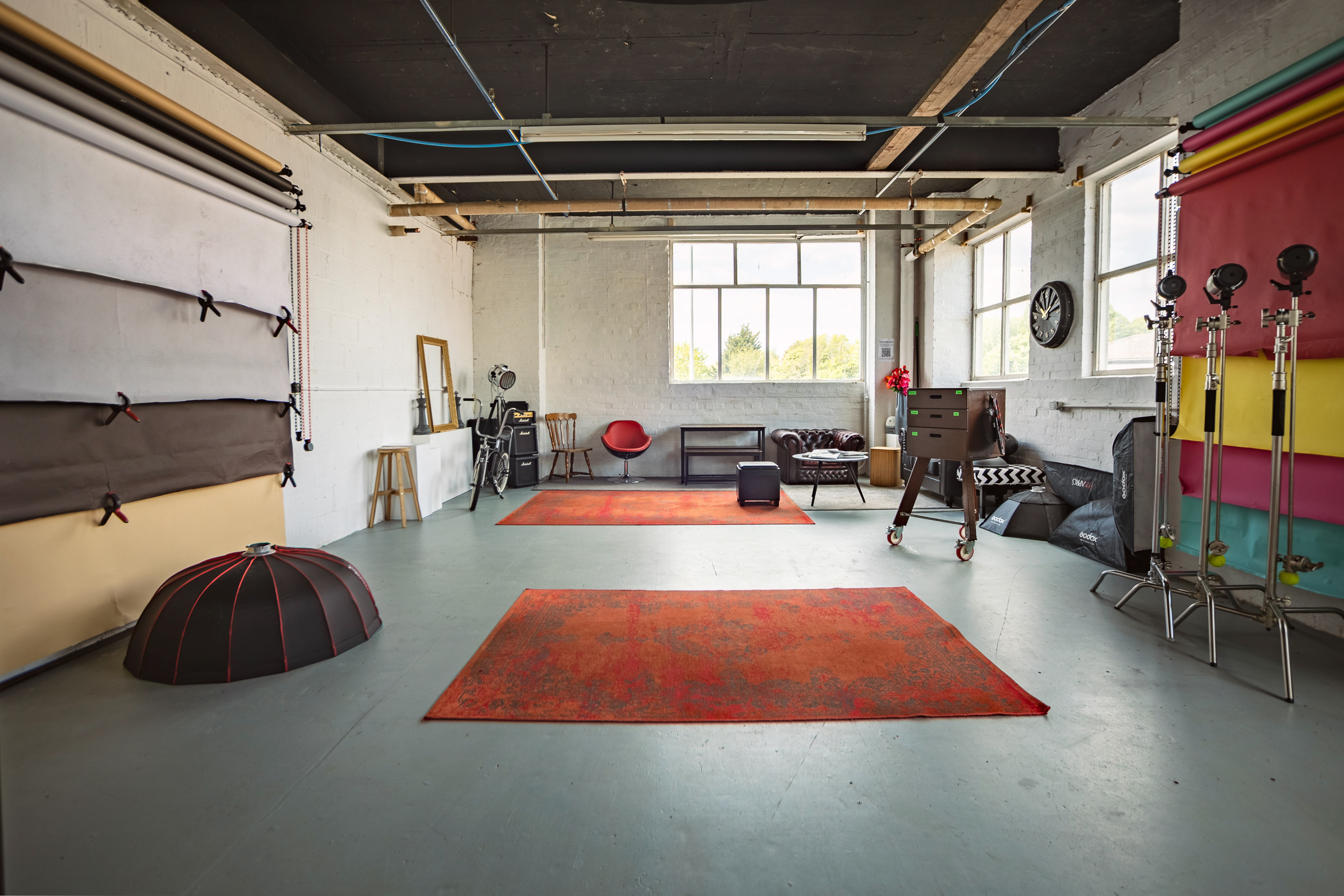 View of a photography studio showing backdrops, lighting, windows and furniture