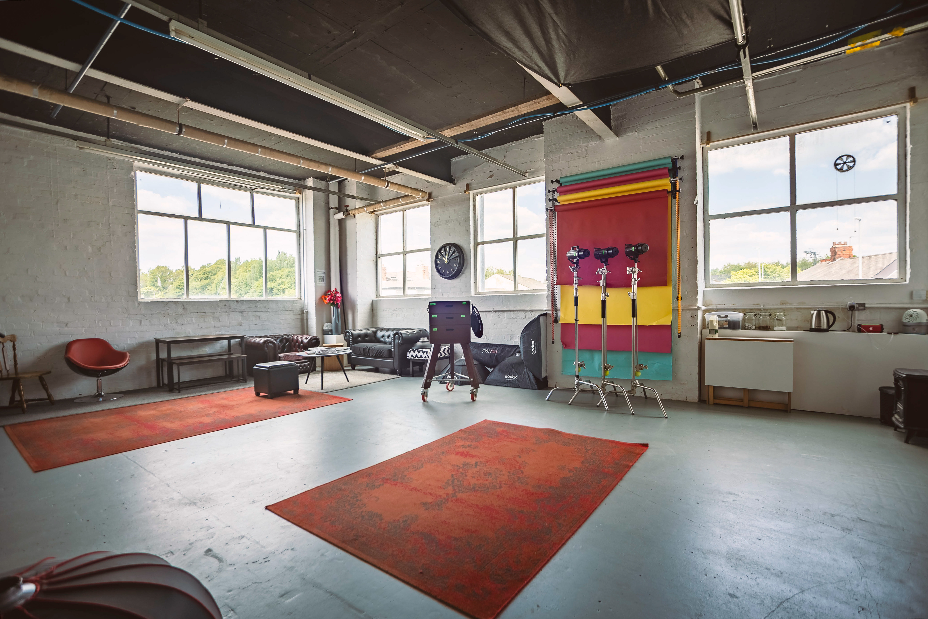 View of a photography studio with large windows, backdrops lights and furniture