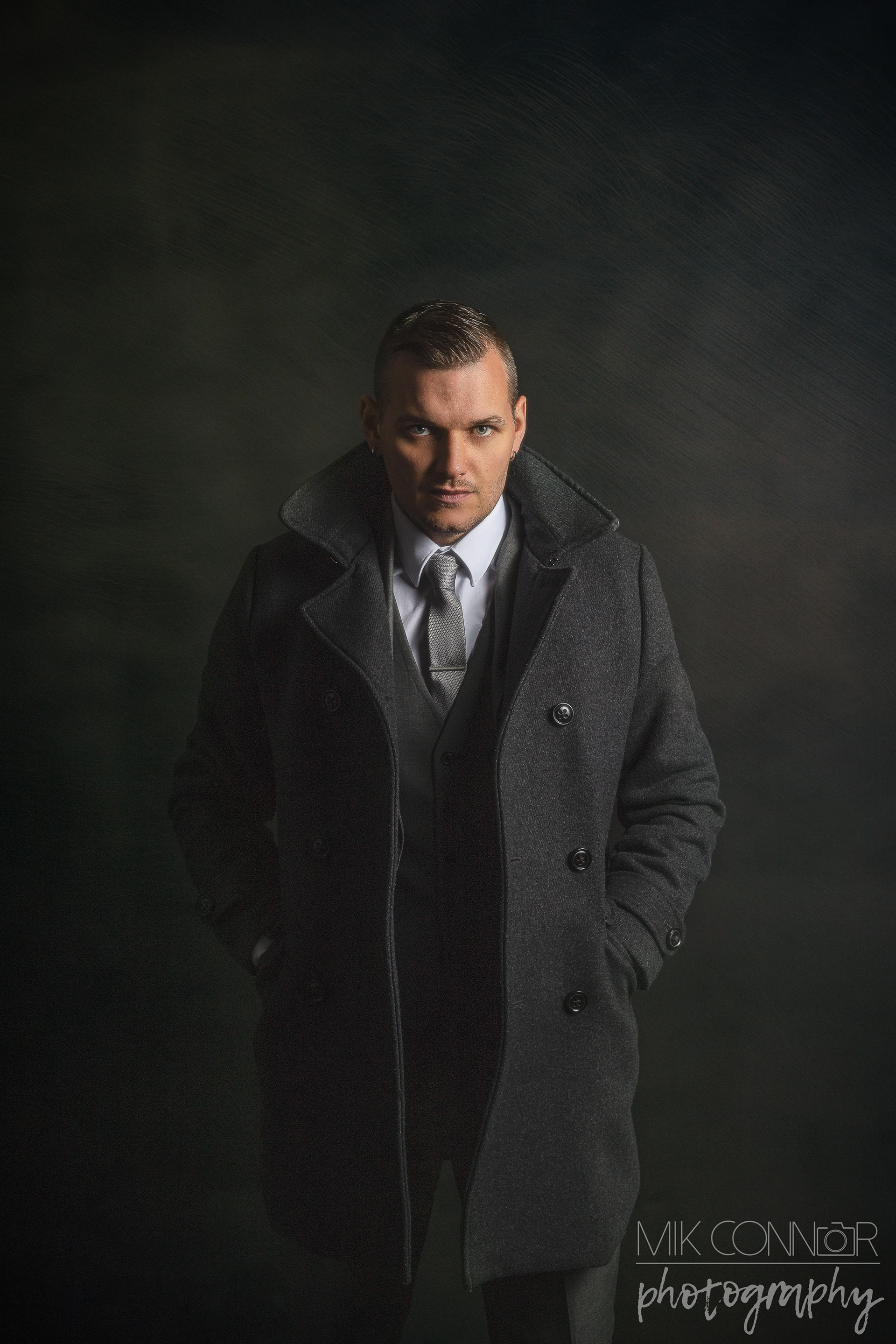Dark and powerful portrait of a male in a three piece suit and a woollen overcoat