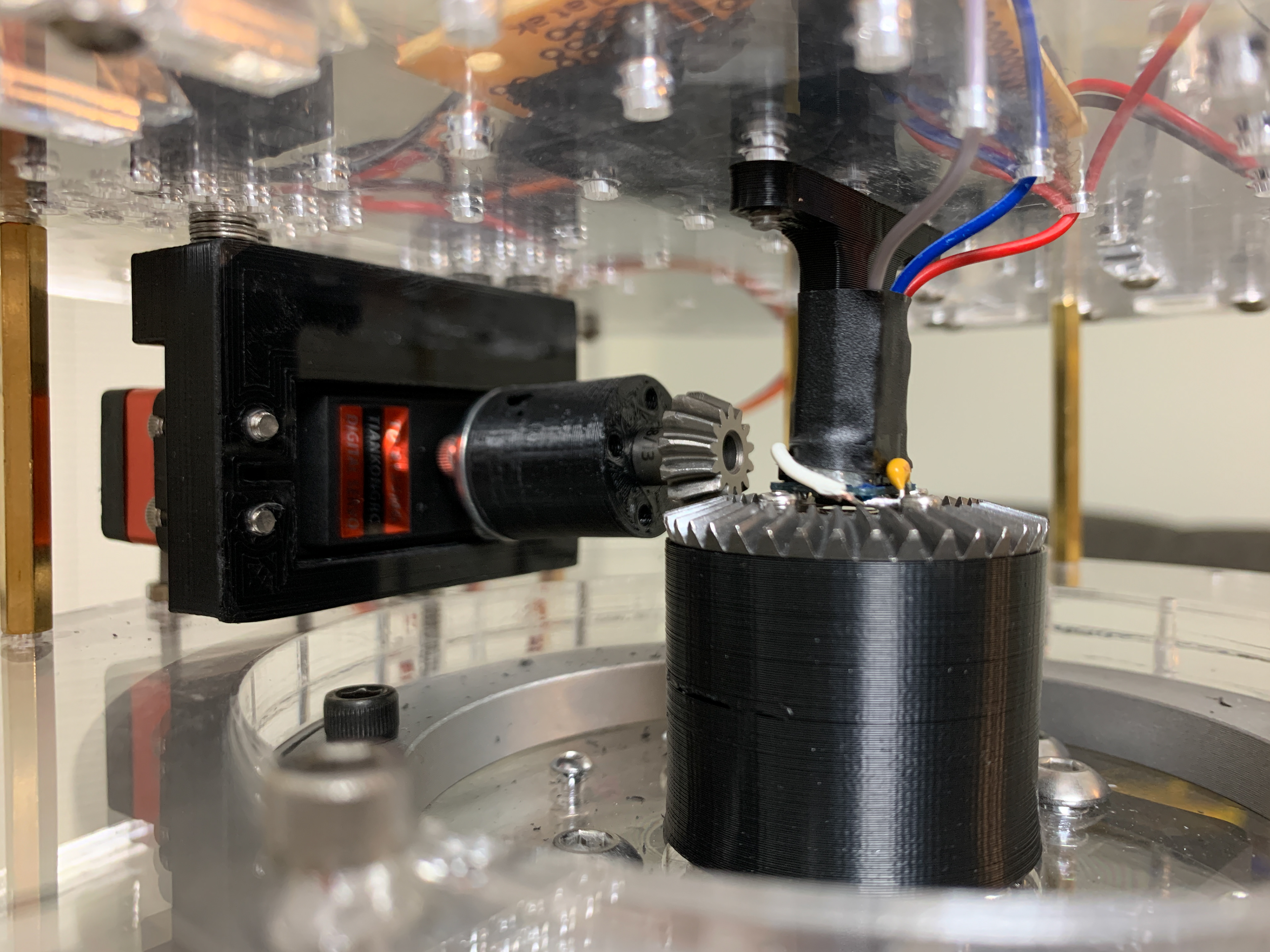 Continuous rotation servo, along with the bevel gears and Hall effect sensor. The larger bevel gear is affixed to the inner ring of the bearing, while the servo is attached to the outer ring through the acrylic plates and brass spacers.