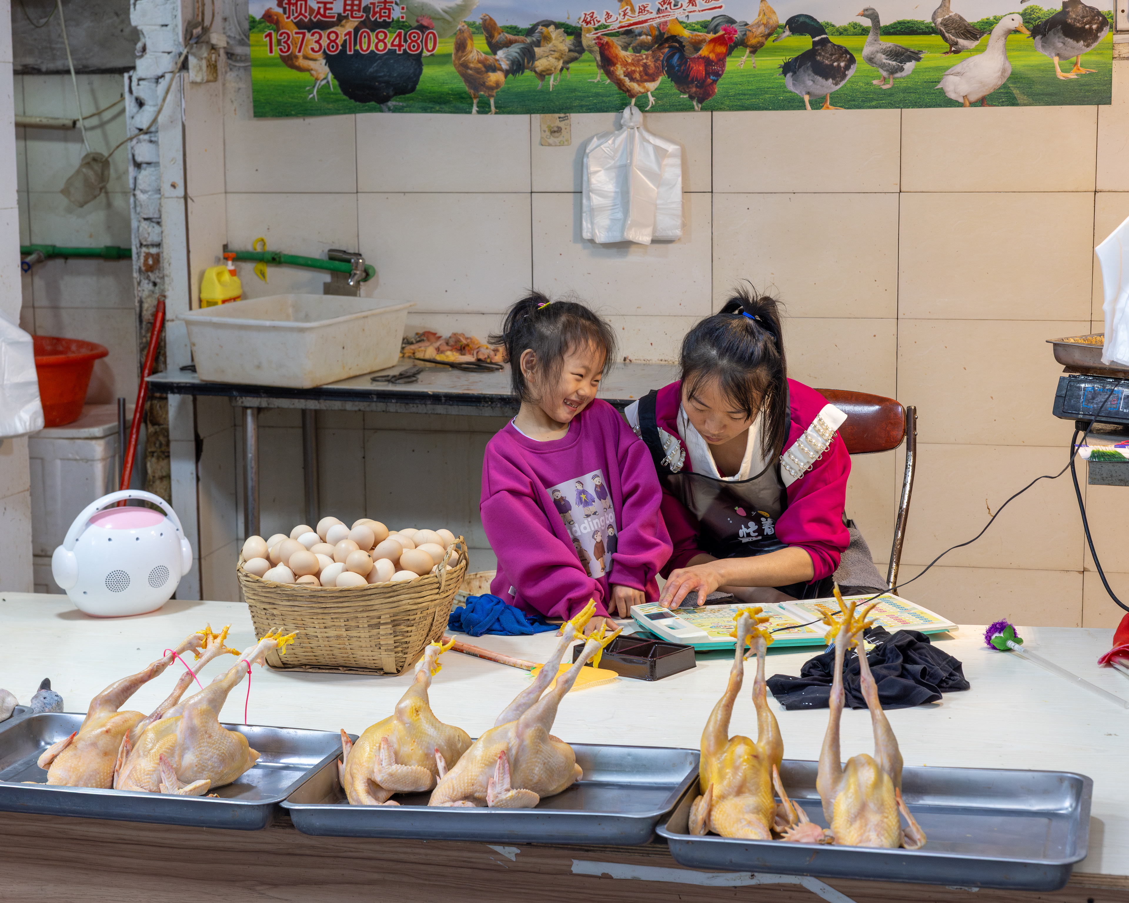 A girl happily doing homework with her mum in their shop, Hangzhou, China