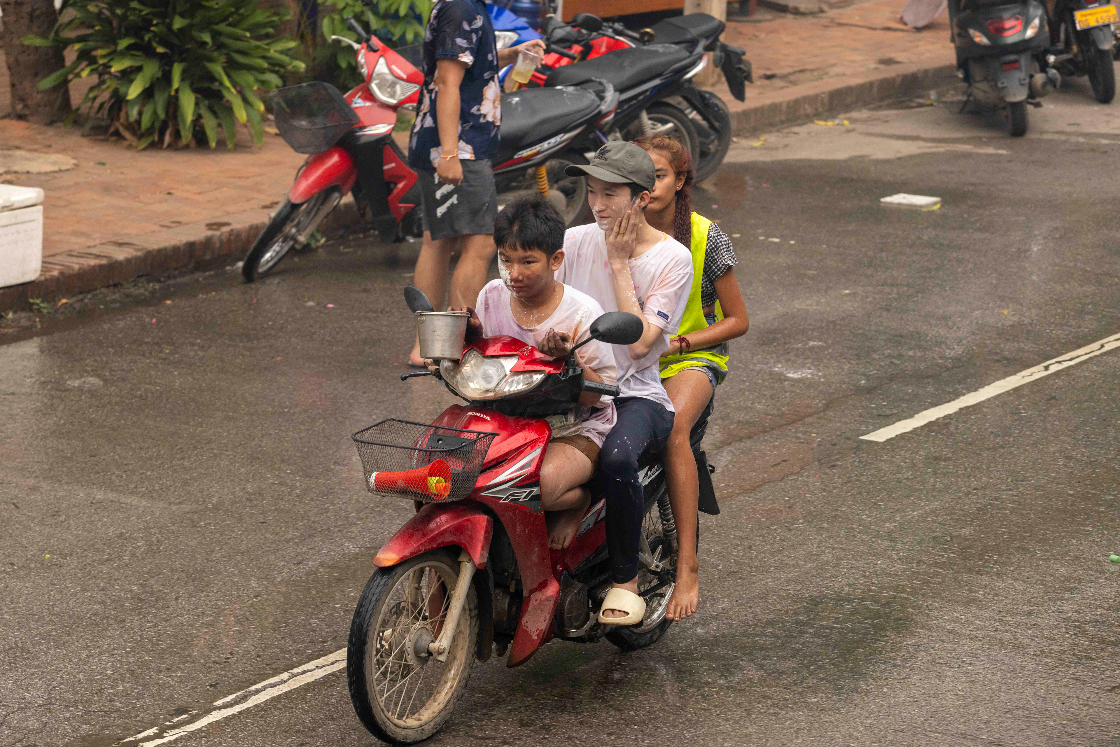 Riders getting splashed by water or chalk during the Water Festival, Luang Prabang, Laos