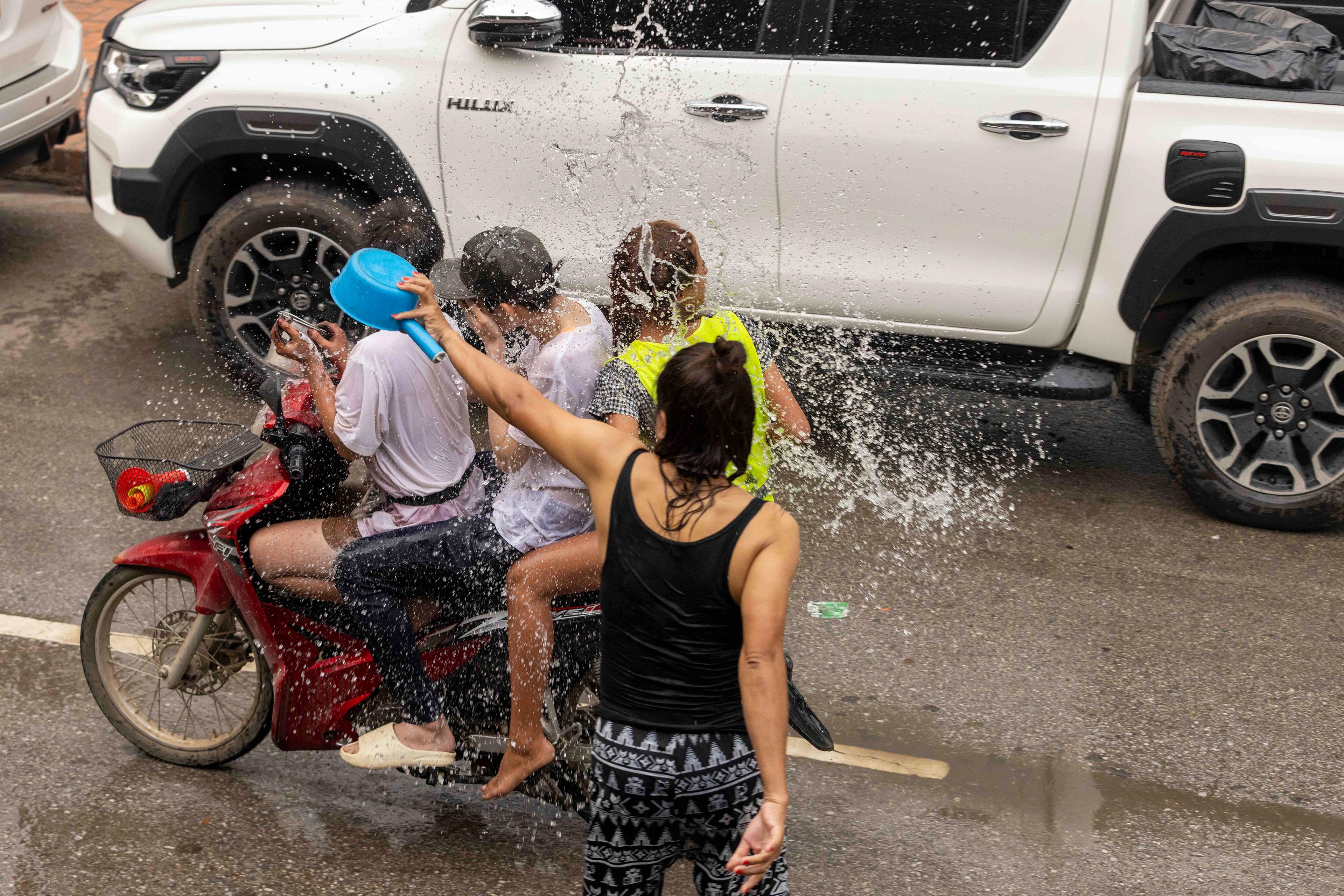 Riders getting splashed by water or chalk during the Water Festival, Luang Prabang, Laos