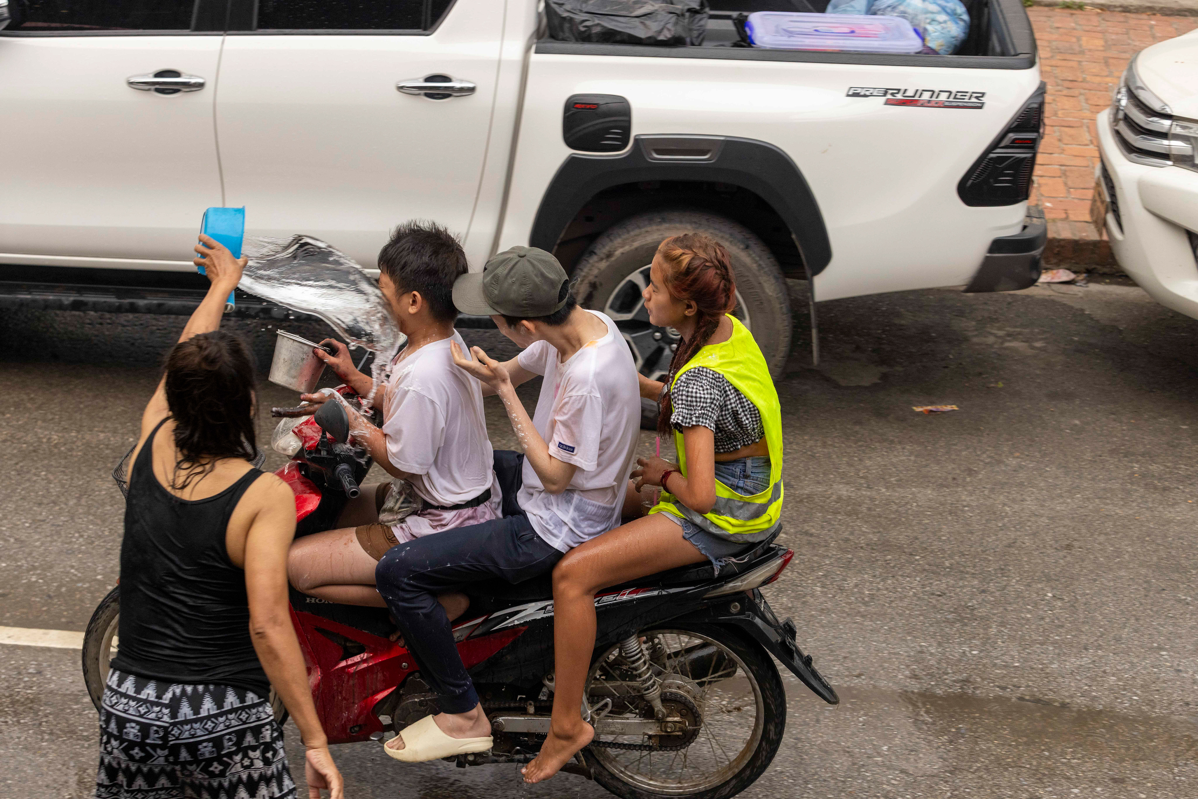 Riders getting splashed by water or chalk during the Water Festival, Luang Prabang, Laos