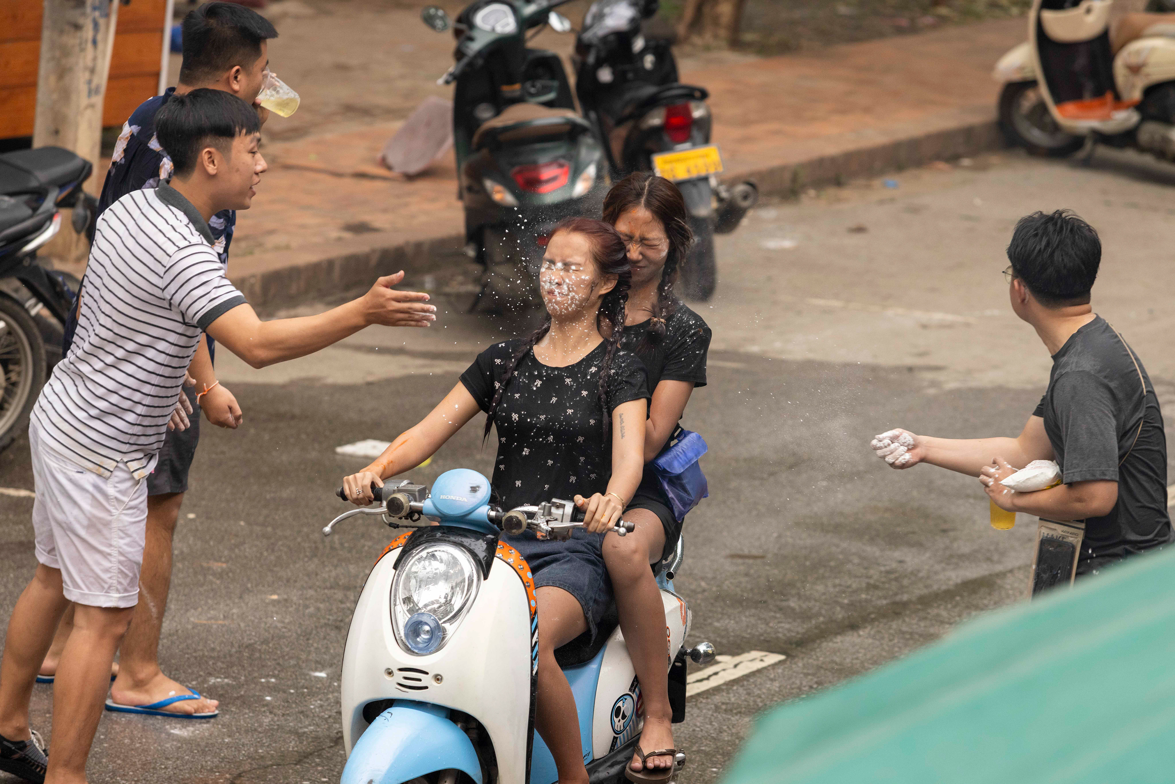 Riders getting splashed by water or chalk during the Water Festival, Luang Prabang, Laos