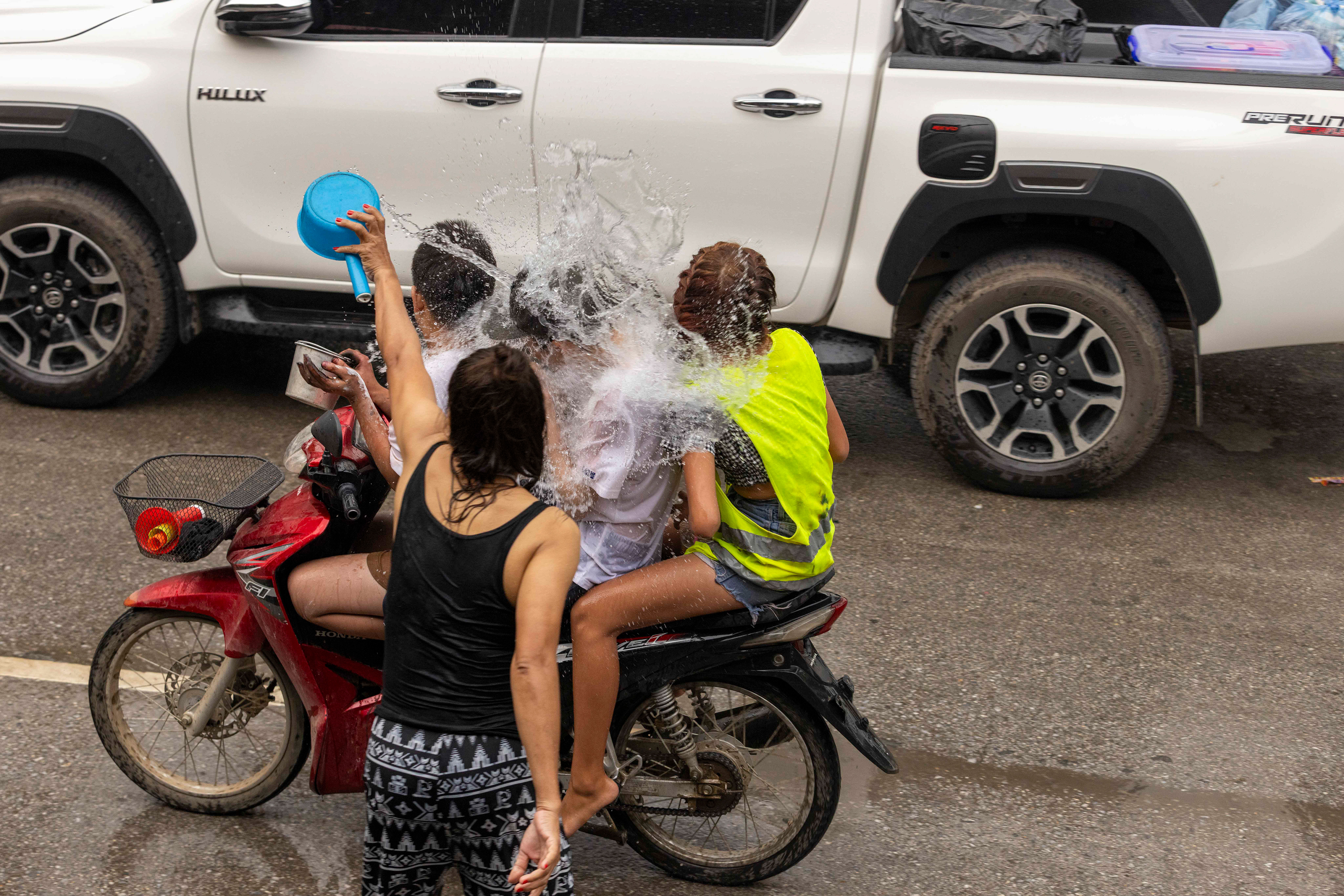 Riders getting splashed by water or chalk during the Water Festival, Luang Prabang, Laos