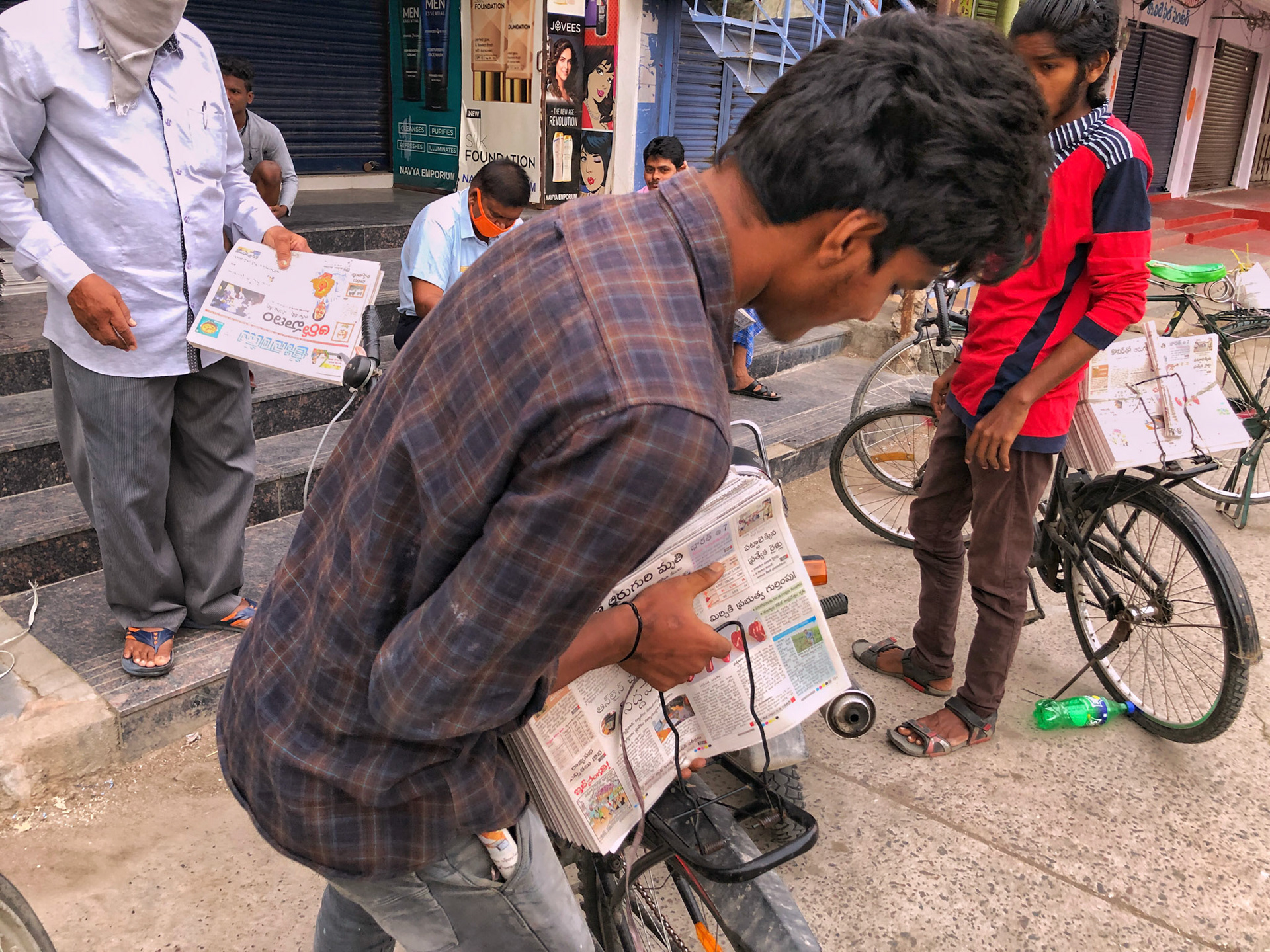 Paperboys loading their cycle with daily newspaper sets. They arrange these papers according to their assigned route.