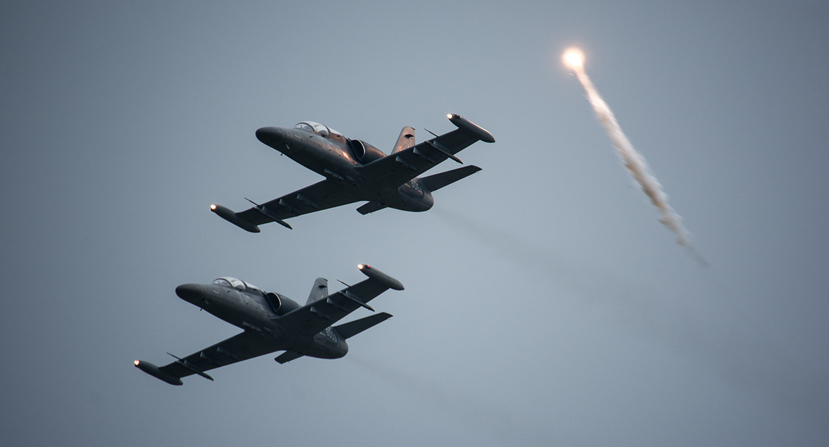 a pair of L159 ALCA launching a flare during a fly by