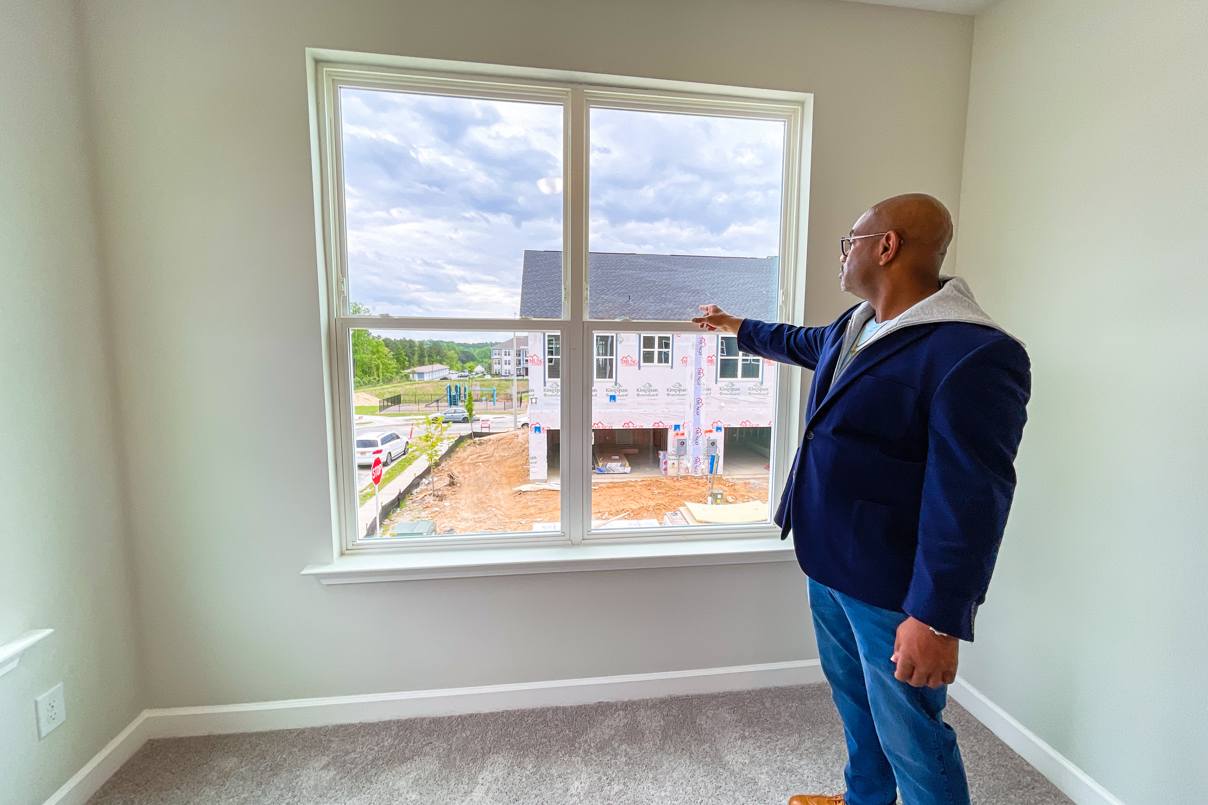 On April 16, 2023, Shawn Mclean recounts the view from a bedroom window in the new townhomes in Knightdale, NC. Some buyers choose end units because you don't get a view of your neighbor's house immediately across the street, but rather a view of other areas as well. (Photo by Jamesha Robinson)