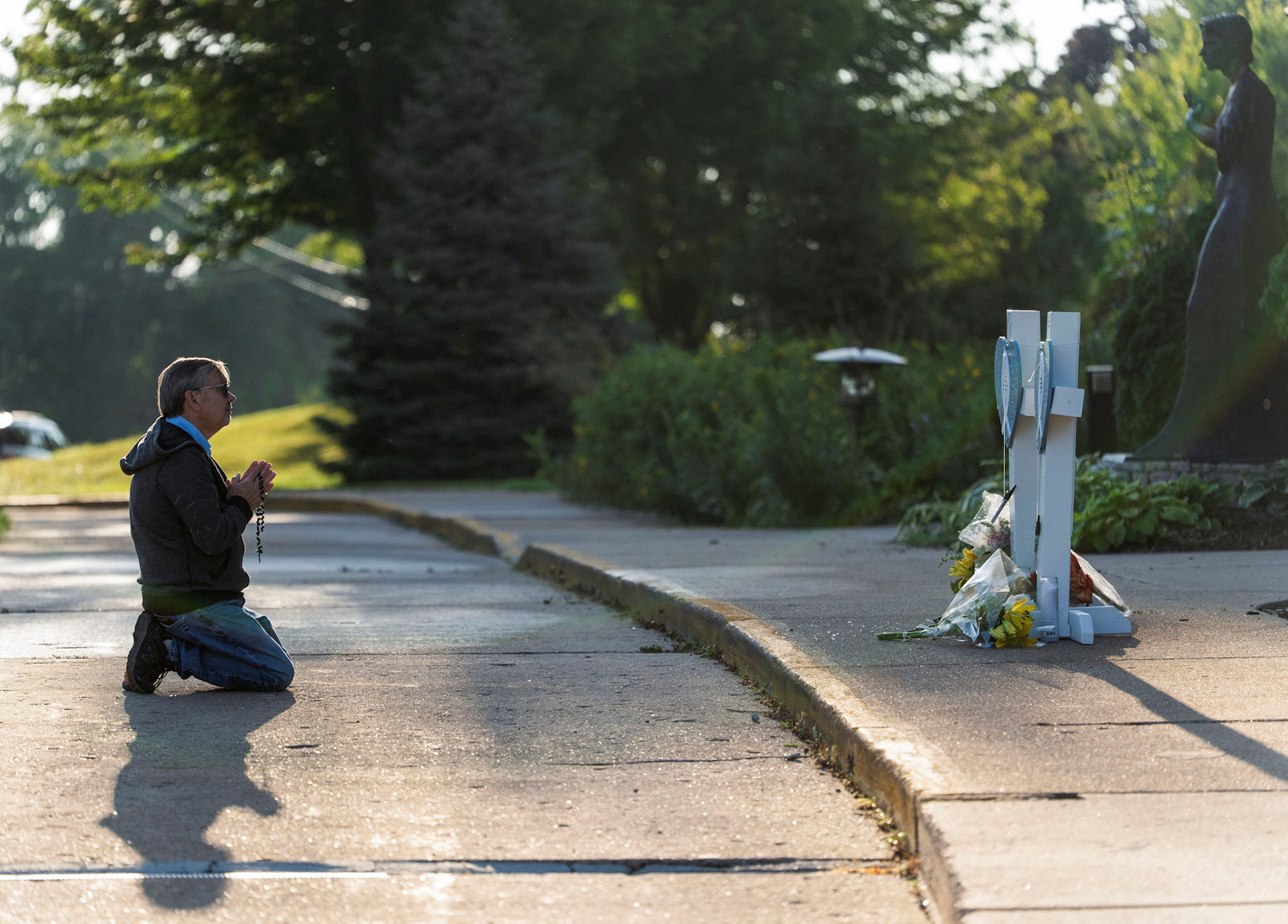 A man prays near crosses outside Annunciation Church in Minneapolis Aug. 28, 2025, following a shooting the previous day. A shooter opened fire with a rifle through the windows of the school's church and struck children attending Mass Aug. 27 during the first week of school, killing two and wounding 21 people in an act of violence the police chief called "absolutely incomprehensible."  (OSV News photo/Tim Evans, Reuters)