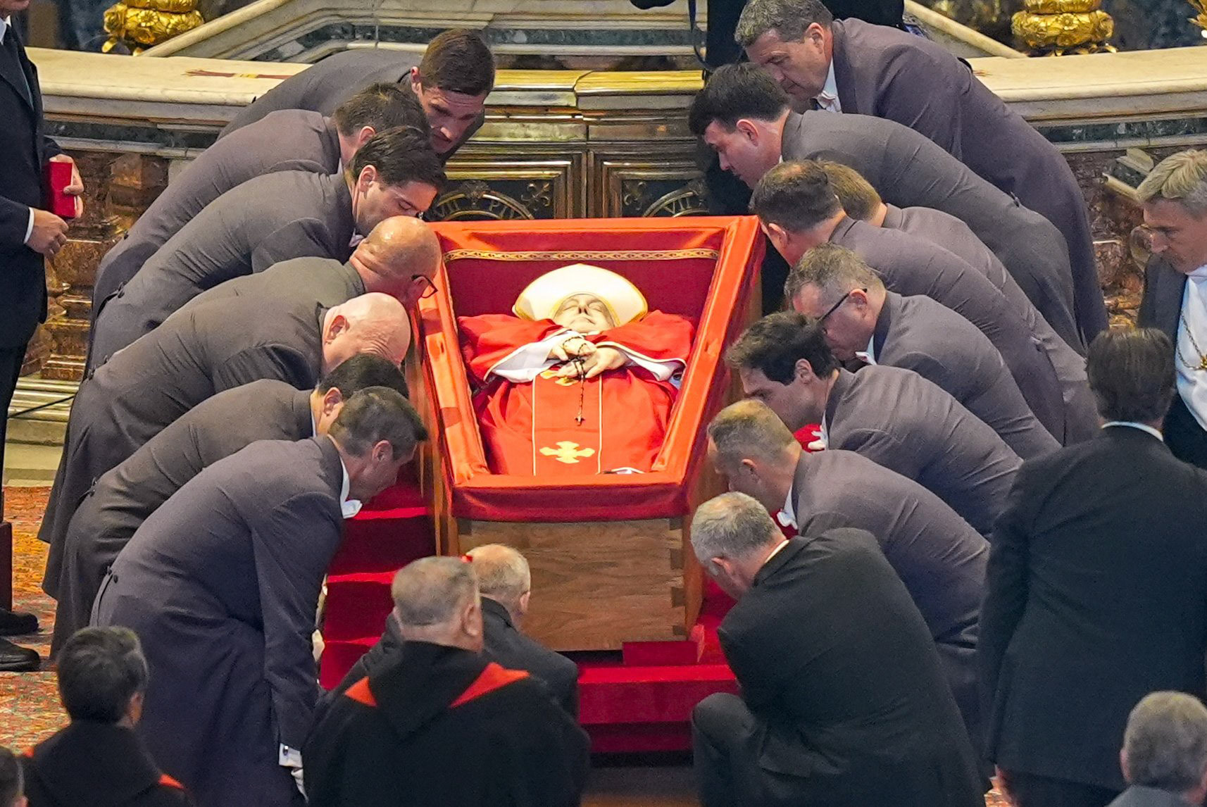 Pallbearers lower the body of Pope Francis, dressed in red liturgical vestments and lying in an open casket, before the Altar of the Confession in St. Peter’s Basilica at the Vatican April 23, 2025. The pope will lie in state for three days of public veneration prior to his funeral Mass April 26. (CNS photo/Lola Gomez)