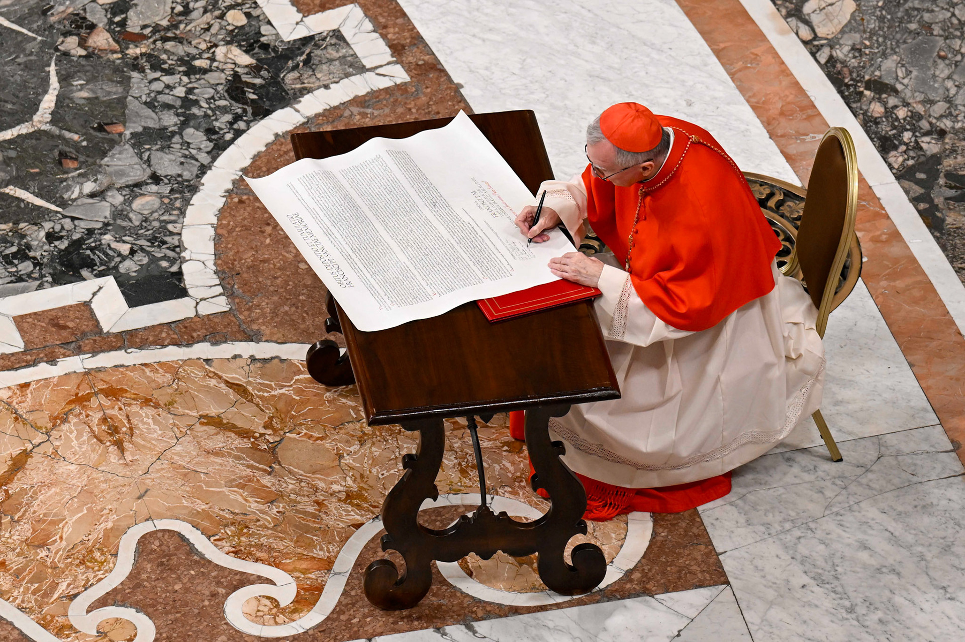 Cardinal Pietro Parolin, Vatican secretary of state under Pope Francis, signs the "rogito" or scroll describing the late pope's life, ministry and papacy April 25, 2025, during a prayer service in St. Peter's Basilica. (CNS photo/Vatican Media)