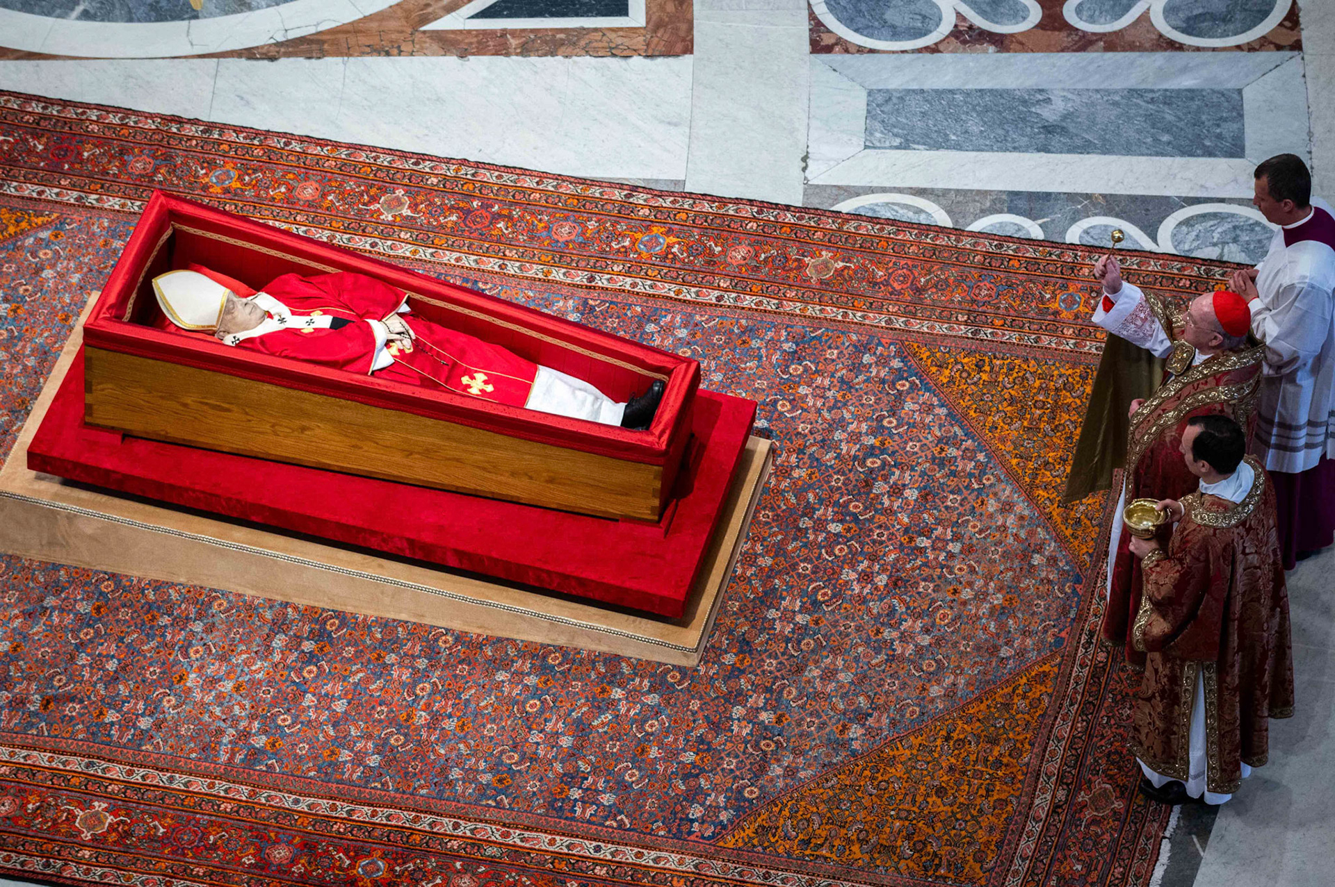 U.S. Cardinal Kevin J. Farrell, camerlengo of the Holy Roman Church, sprinkles holy water over the body of Pope Francis in St. Peter’s Basilica at the Vatican April 23, 2025. The pope, in an open casket, will lie in state for public viewing and prayer for three days ahead of his funeral Mass April 26. (CNS photo/Paolo Galosi, pool)