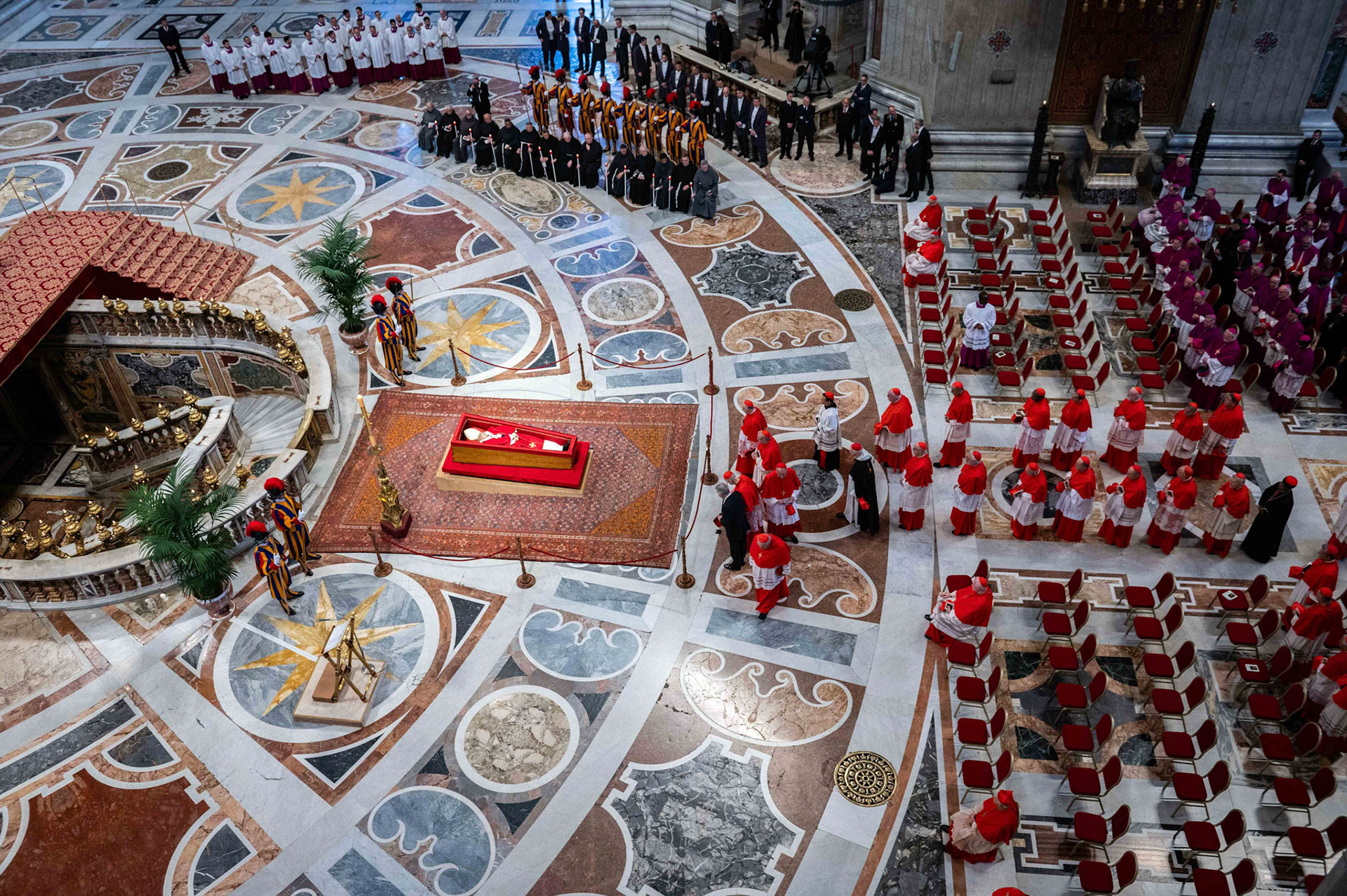 Cardinals process past the body of Pope Francis as he lies in state in an open casket in front of the Altar of the Confession in St. Peter’s Basilica at the Vatican April 23, 2025. The pope will lie in state for three days of public viewing and prayer ahead of his funeral Mass April 26. (CNS photo/Paolo Galosi, pool)