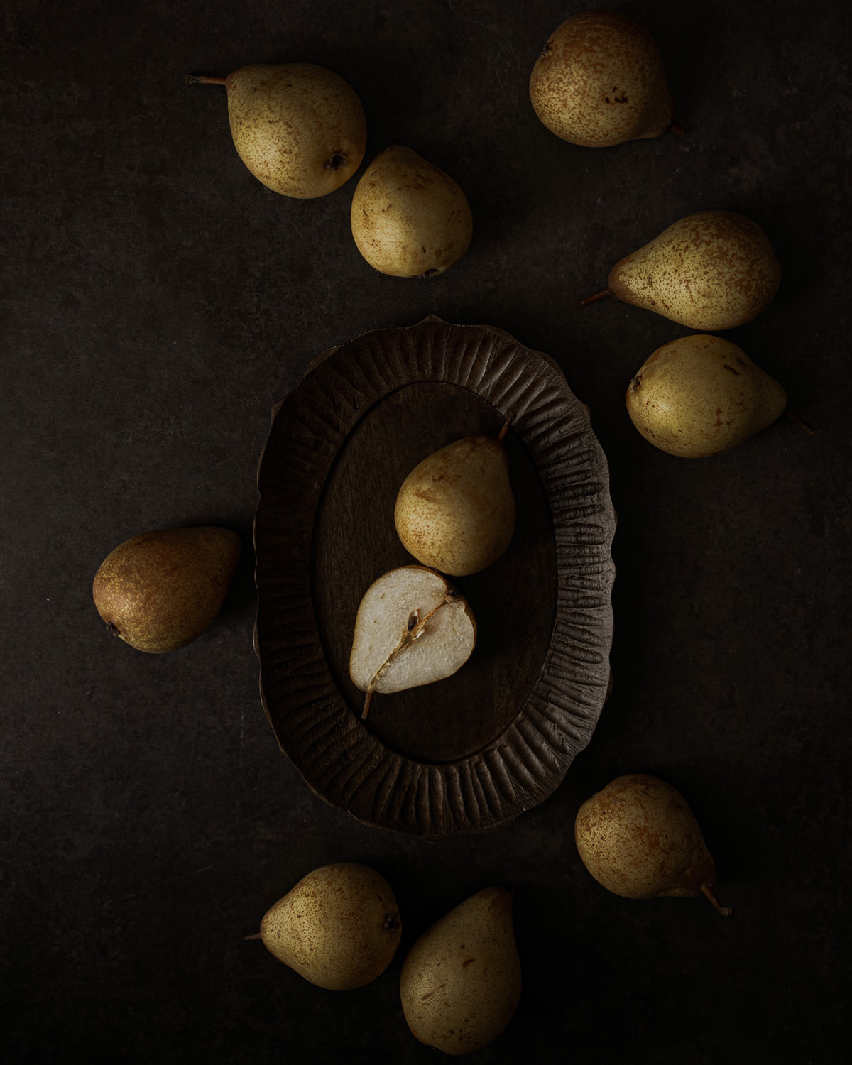 Pears scattered on table, pear half in middle on wooden bowl, old masters style painting
