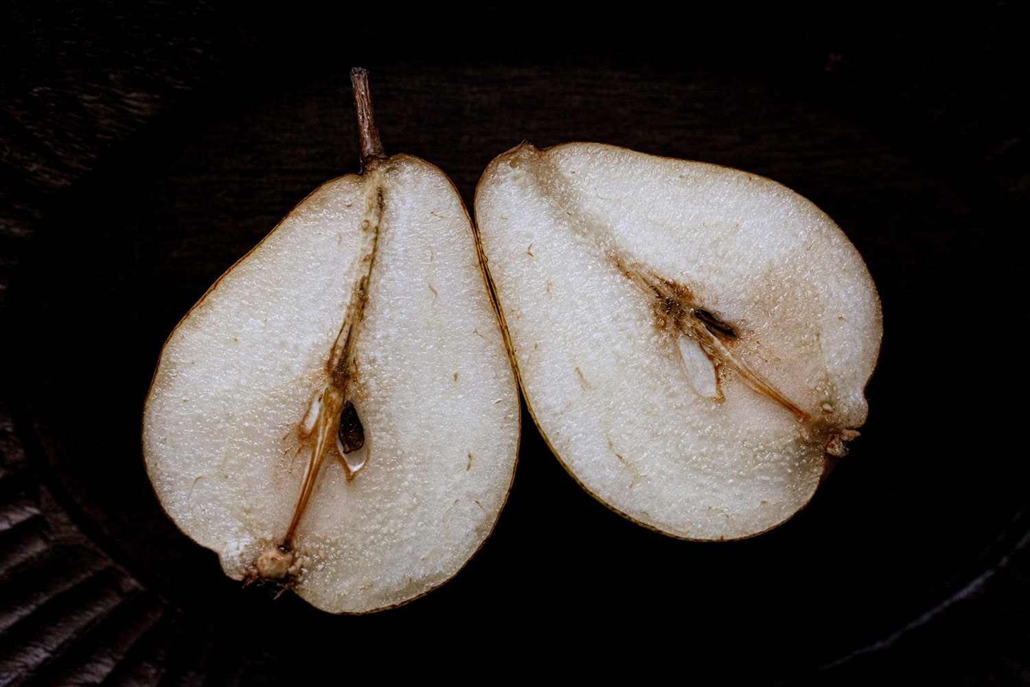two white pear halves on dark background