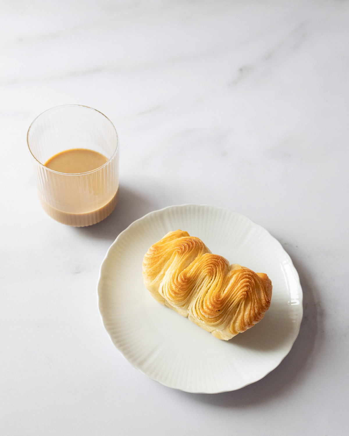 Top view of brioche with a glass of oat milk coffee.