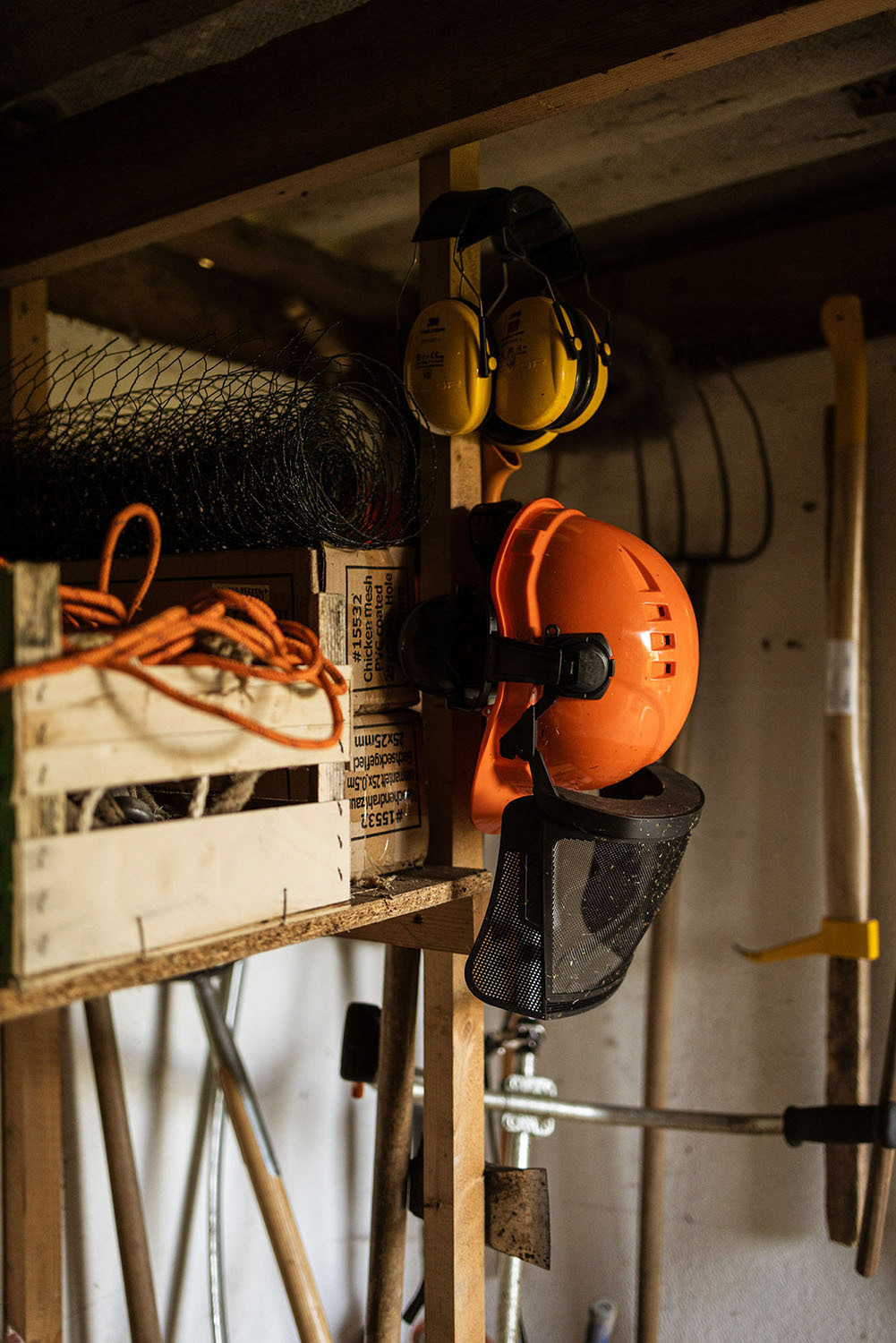 Orange and yellow protective gear for the head and ears in a garden shed.