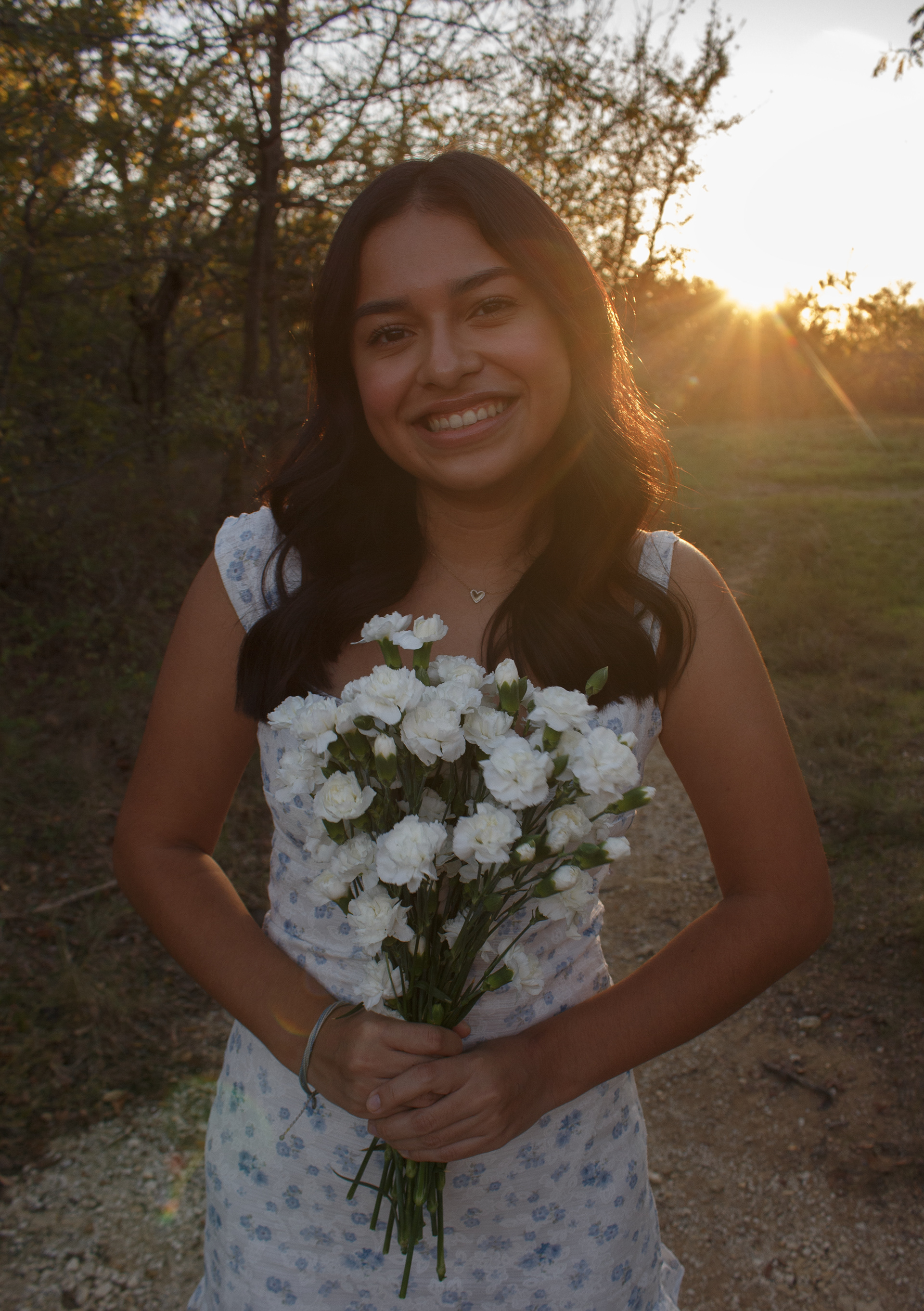 With her bouquet presented in front of her, Gabriela Alaniz smiles as the sun sets behind her during her senior portrait session at Arbor Hills Nature Preserve on Nov. 10, 2024. Photo/ Natalie VanDerWal