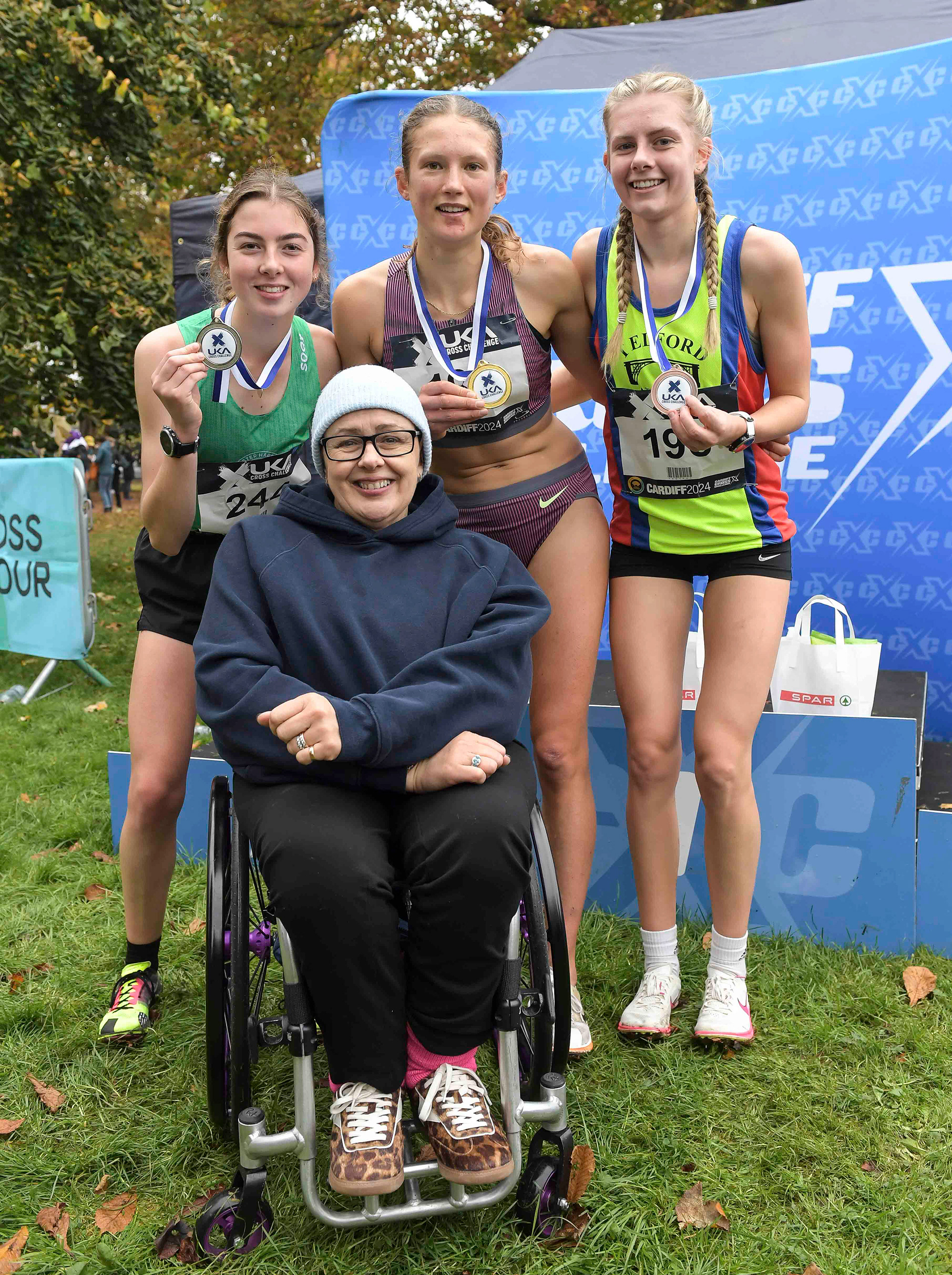 Tanni Grey-Thompson with Lizzie Wellsted (2nd) Innes FitzGerald (1st) and Zoe Gilbody (3rd) at the U17/U20 women’s medal presentation at the Cardiff Cross Challenge inc World Athletics Cross Country Tour (Gold Label), Llandaff Fields, Cardiff, Wales on the 9th November 2024