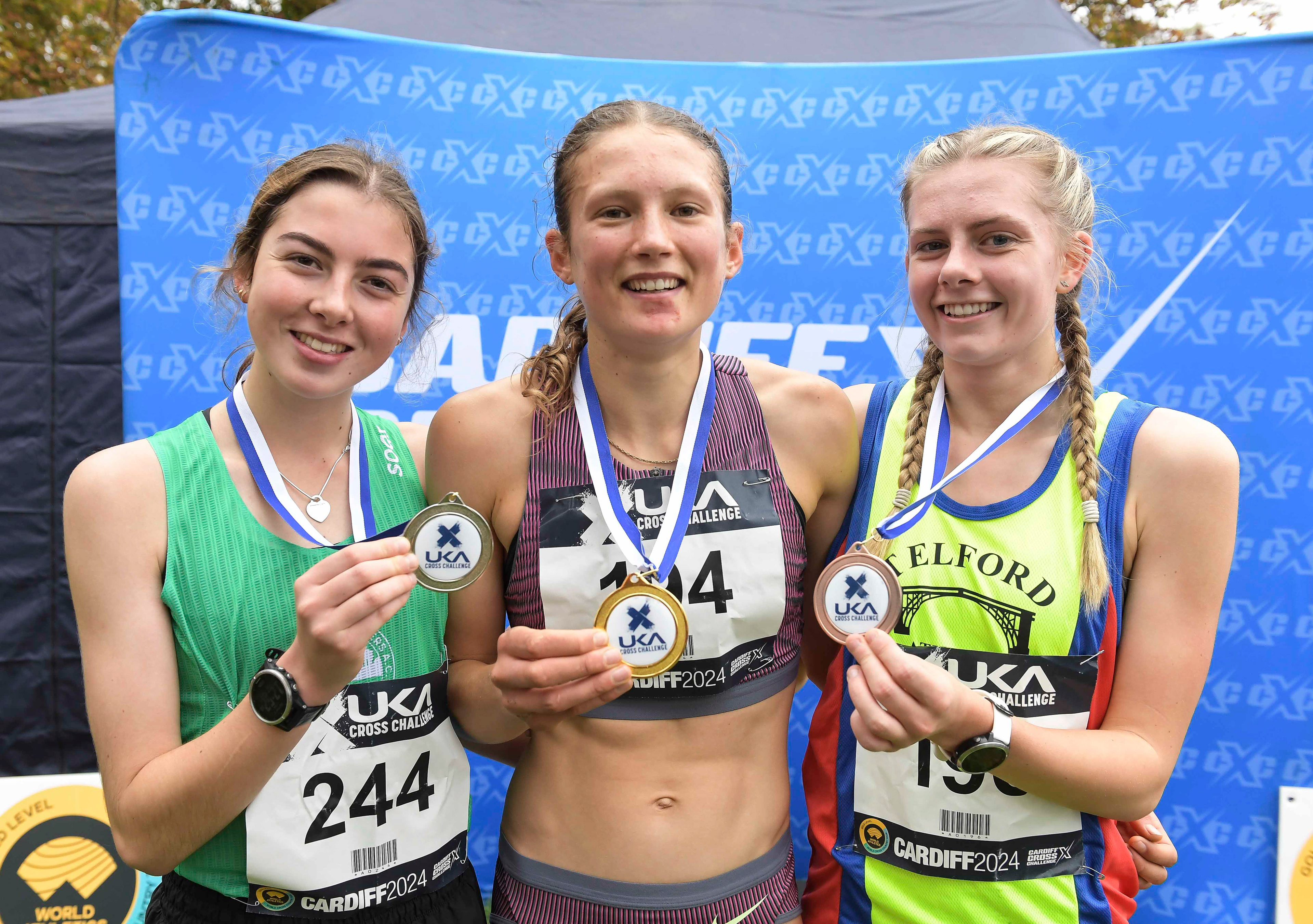 Lizzie Wellsted (2nd) Innes FitzGerald (1st) and Zoe Gilbody (3rd) at the U17/U20 women’s medal presentation at the Cardiff Cross Challenge inc World Athletics Cross Country Tour (Gold Label), Llandaff Fields, Cardiff, Wales on the 9th November 2024