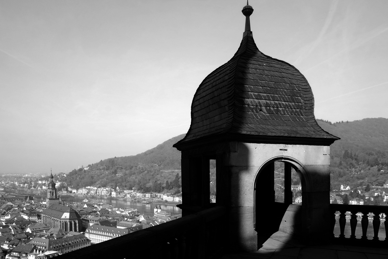 Black and white photograph of a tower in half shadow above the city of Heidelberg, Germany.