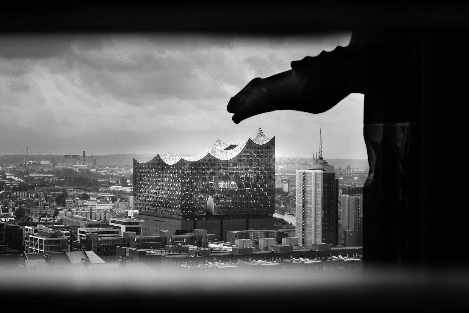 Black and white photograph by Mark Robert Davey showing a Gargoyle keeping Watch on the Elphi opera house in Hamburg.