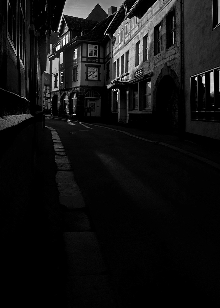 Black and white photograph of an old street and houses with dramatic street lighting in Goslar, Germany.