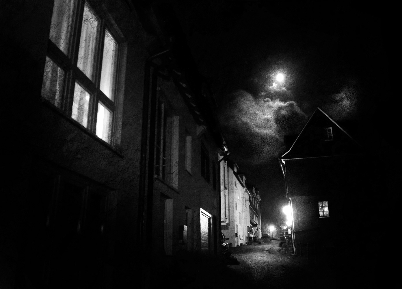 Black and white photograph at night of a full moon over the old city area of Siegen, Germany