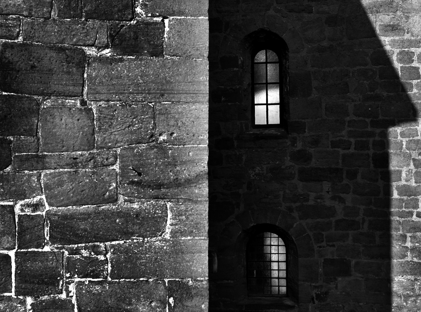 Black and white photograph of a building with a perfect hand shadow.