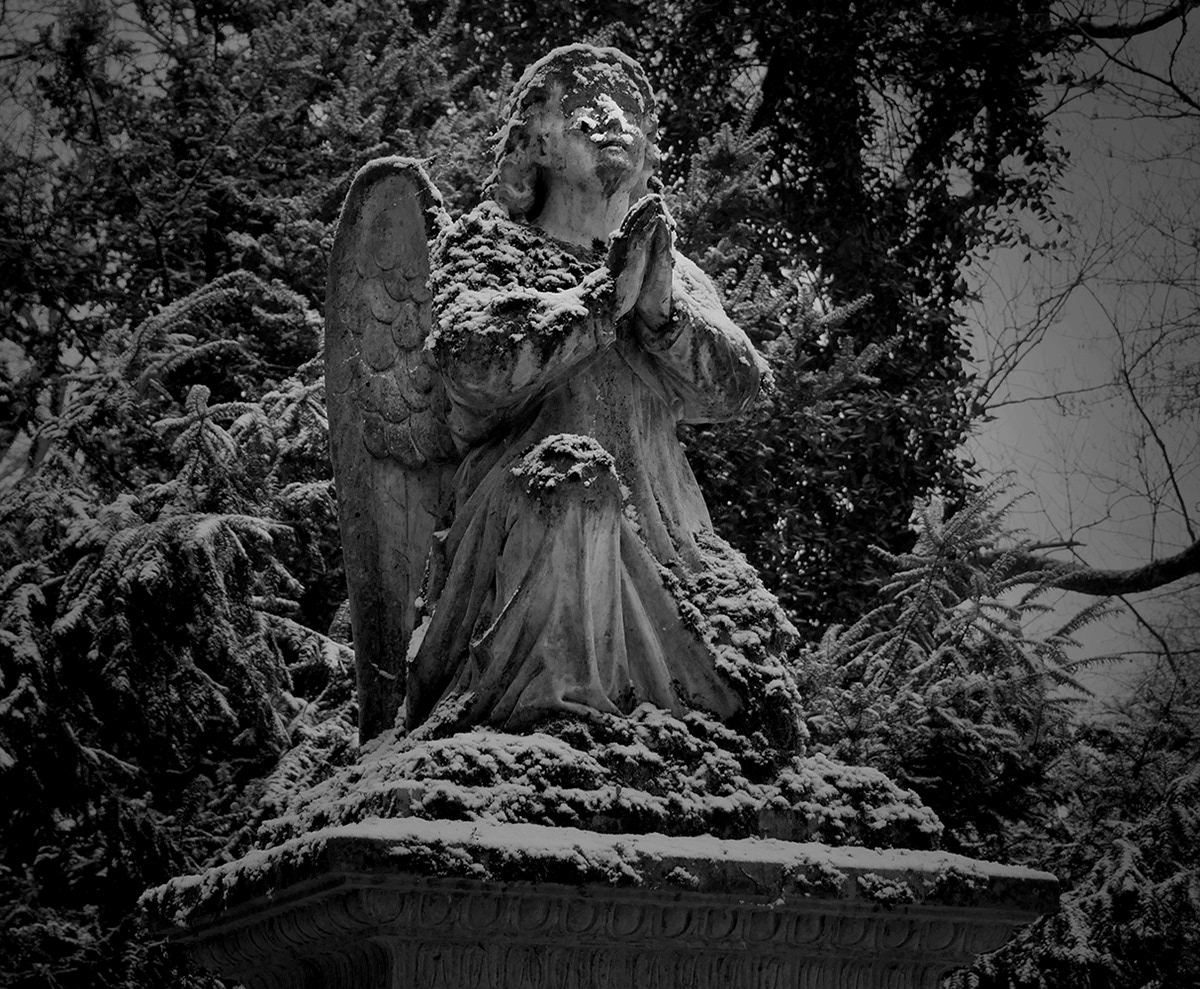 Black and white photograph of a snow covered cemetery angel in Kortumpark Bochum Germany