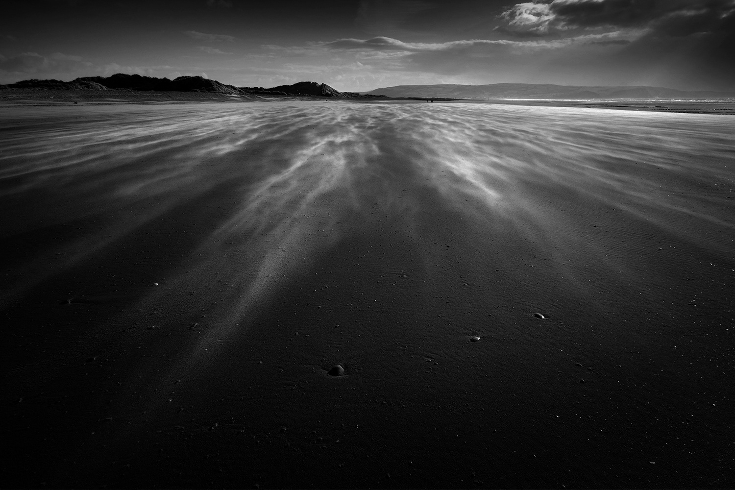 Black and white photograph of sand blowing over the beach in Aberdyfi, Wales.
