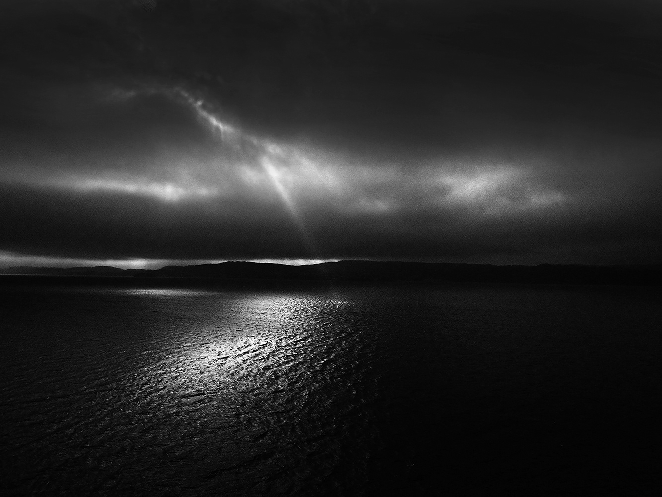 Black and white photograph of dramatic light and clouds over the Fjord in Norway.