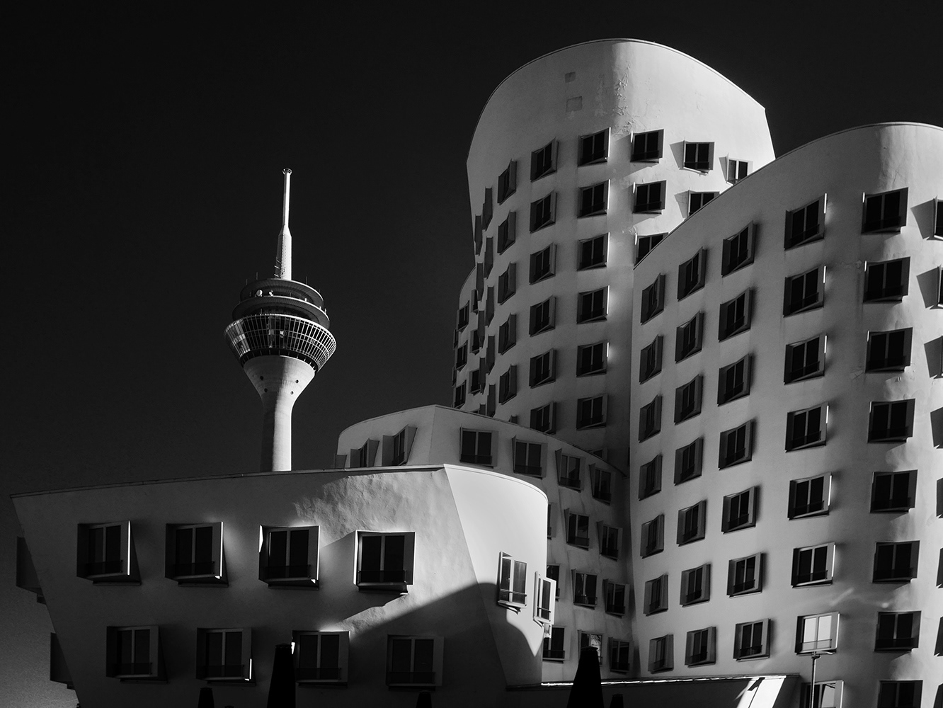 Black and white photograph of the Gehry building and Rheineturm in Dusseldorf