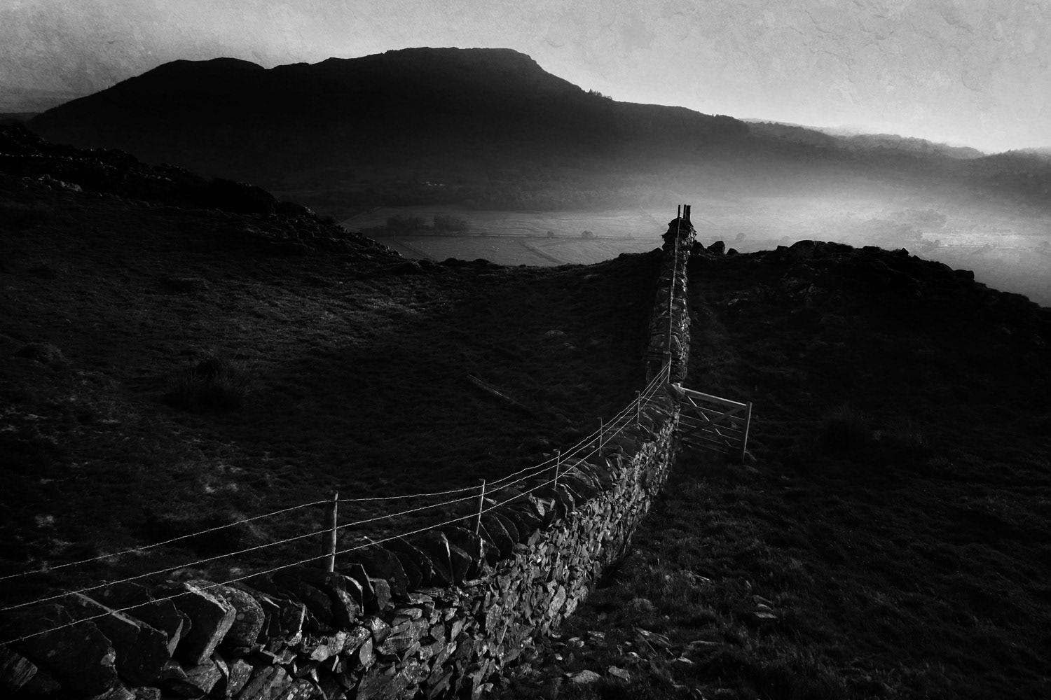 Black and white photograph of a wall and mountain with mist rising, Moel y Gest, Wales, UK