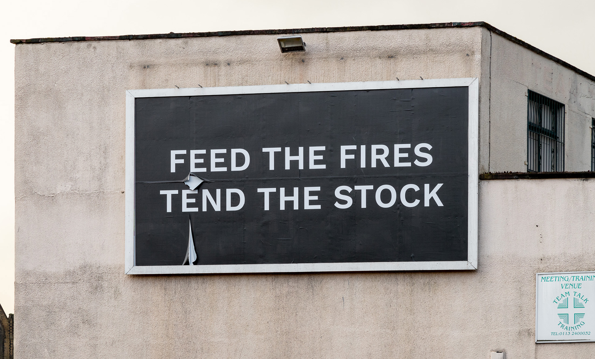 A billboard situated in Leeds, it says 'Feed the fires, tend the stock'