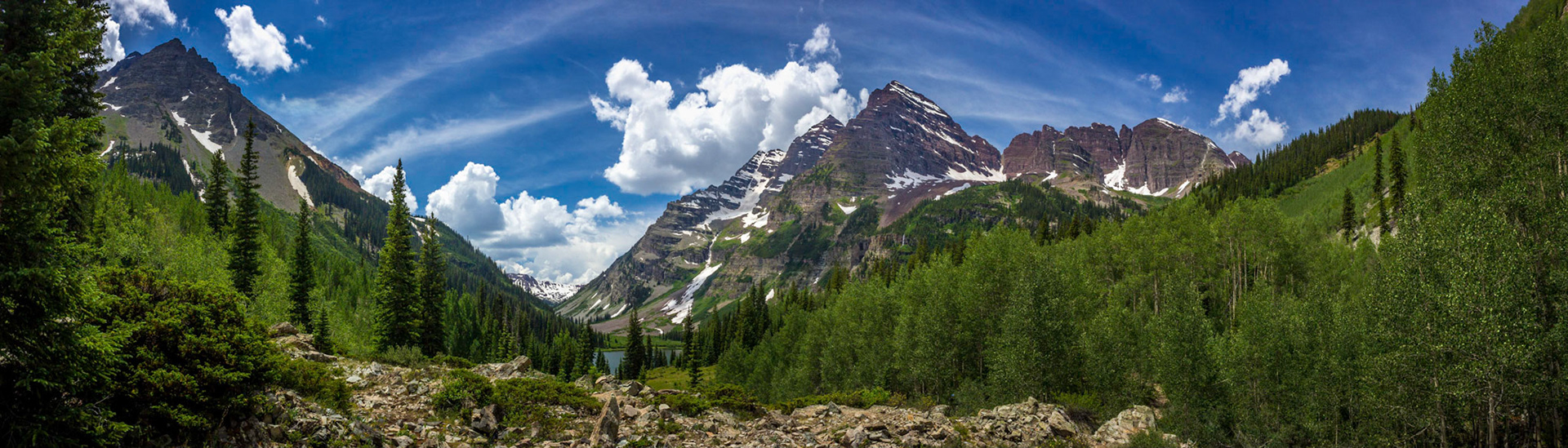 Stunning Maroon Bells and Crater Lake in Snowmass Wilderness in Aspen, Colorado with a blue sky and clouds in summer